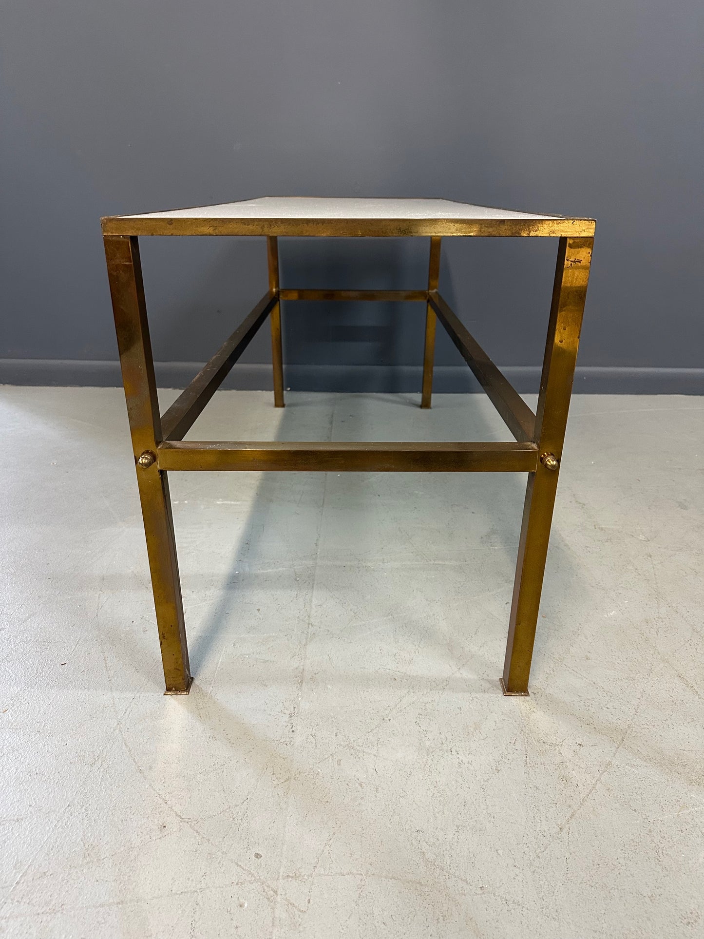 1970s brass console table featuring a sleek white Vitrolite glass top and a minimalist rectangular brass frame with clean lines and mid-century modern influence