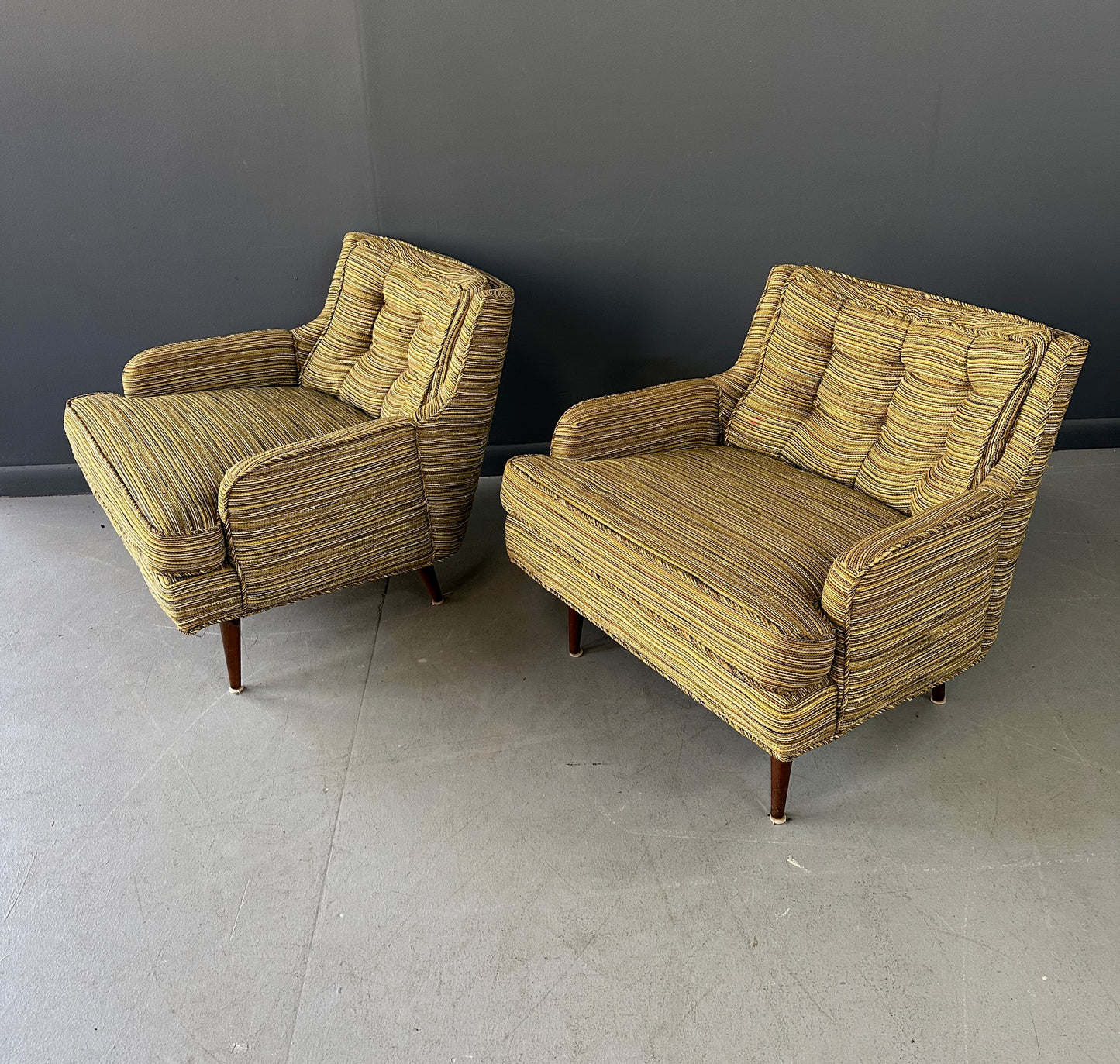 Pair of mid-century lounge chairs with tapered walnut legs, upholstered in original striped multicolor fabric with tufted backs and plush cushions