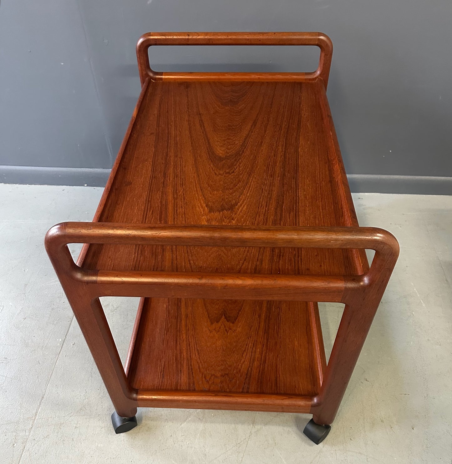 Vintage Danish teak mid-century modern bar cart or drinks trolley with two-tier design, rolling wheels, and minimalist Scandinavian style