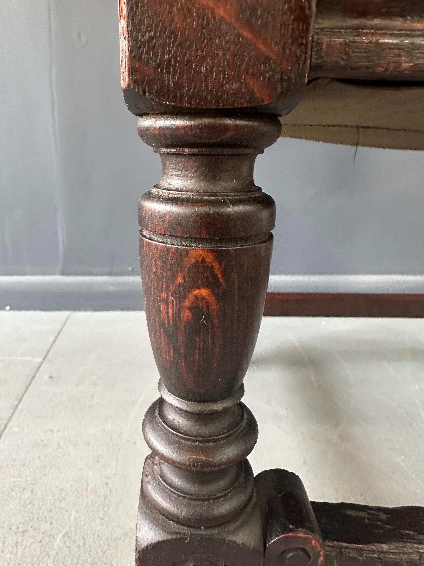 Impressive English 18th-century oak carved armchair featuring tooled leather backrest with heraldic motif, nailhead trim, and ornate turned wood detailing