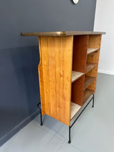 Load image into Gallery viewer, Mid-Century Modern dry bar console with matching stool by Arthur Umanoff, 1950s, featuring slatted wood panels, iron legs, and a curved wooden seat and backrest with minimalist black metal framing