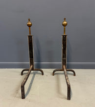 Load image into Gallery viewer, Pair of Machine Age andirons made of polished steel columns with spherical brass finials on top, supported by rugged iron bases with a minimalist, industrial design.