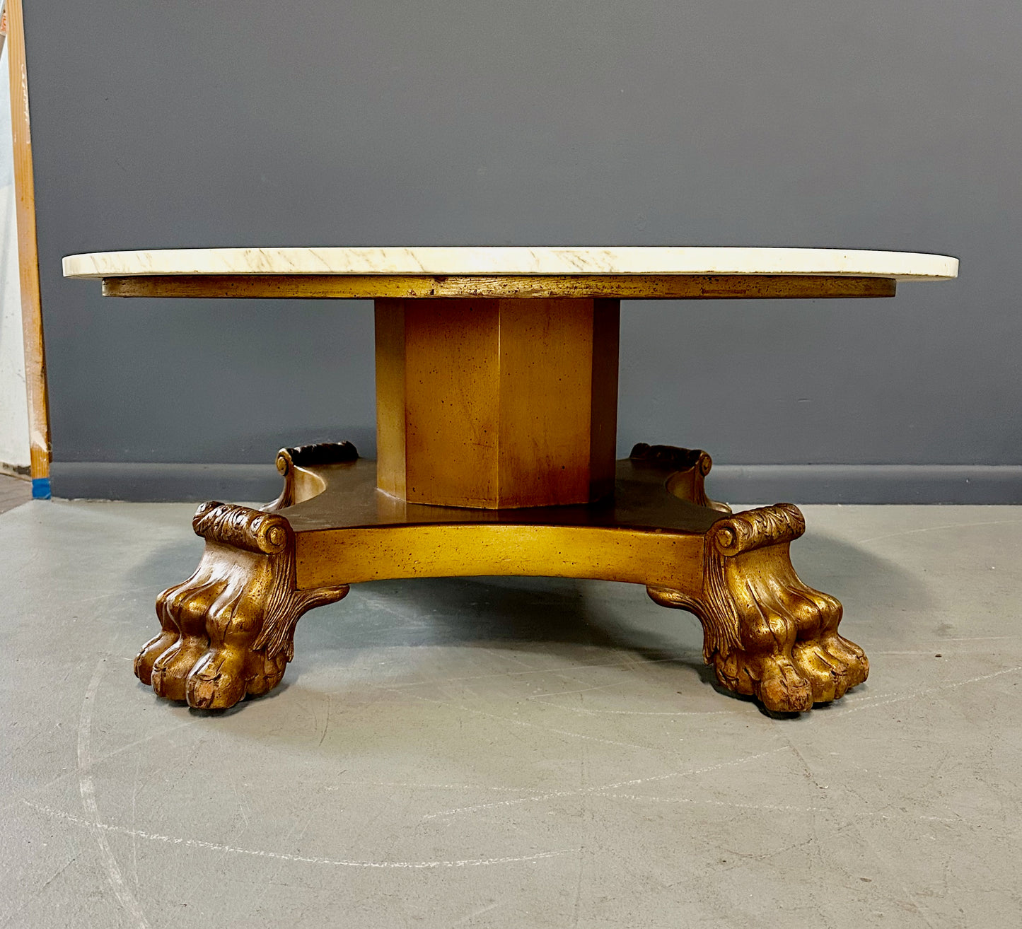 20th-century Empire-style Hollywood Regency coffee table featuring a round white marble top with elegant gray veining, supported by a gilded wood base with bold lion paw feet and neoclassical design elements