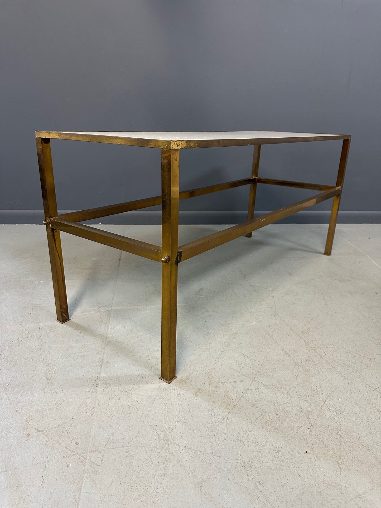 1970s brass console table featuring a sleek white Vitrolite glass top and a minimalist rectangular brass frame with clean lines and mid-century modern influence