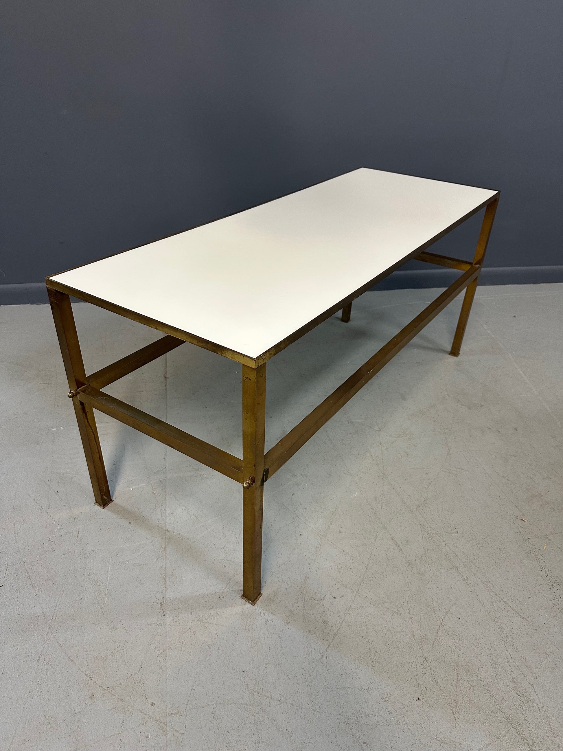 1970s brass console table featuring a sleek white Vitrolite glass top and a minimalist rectangular brass frame with clean lines and mid-century modern influence