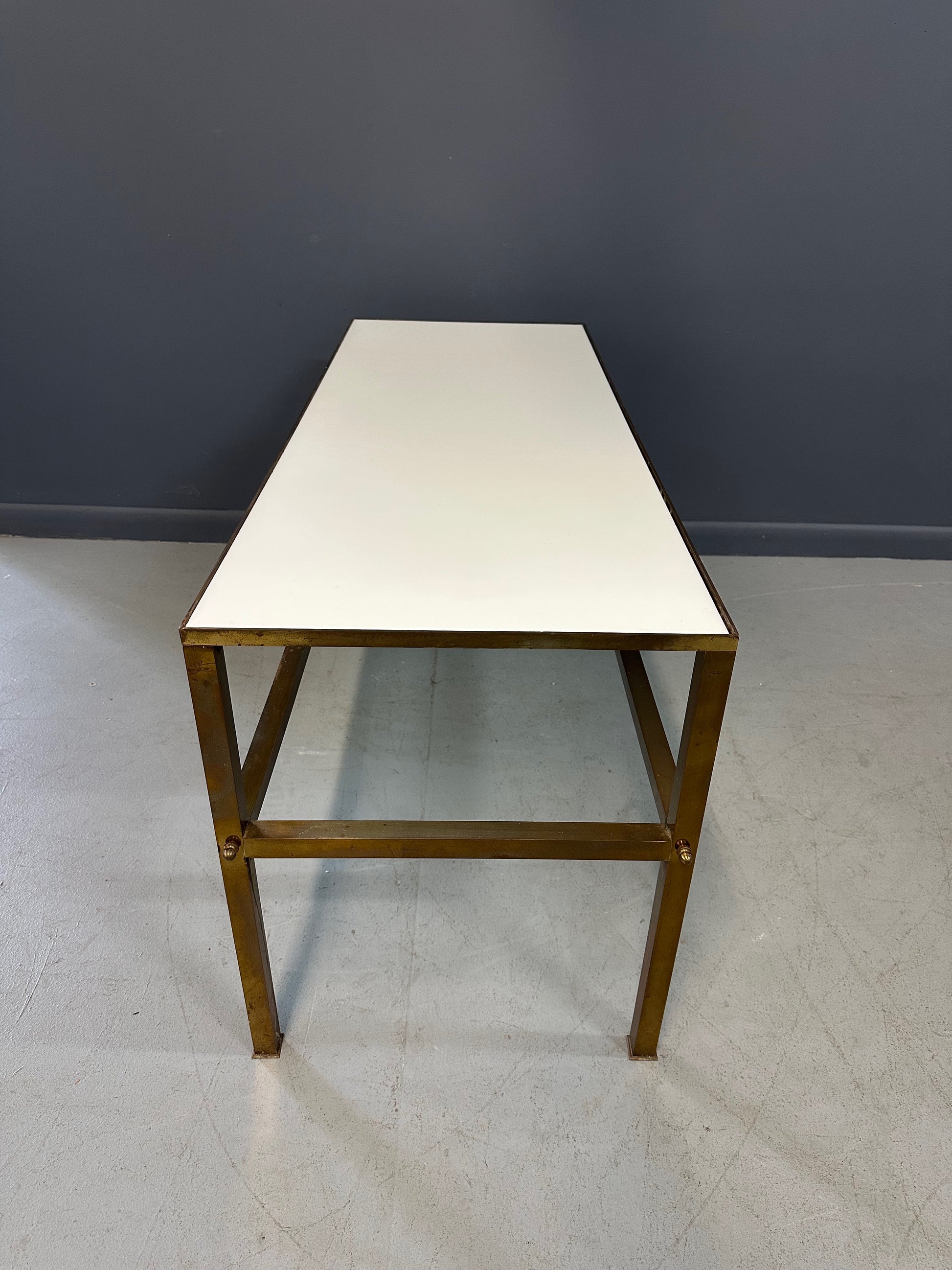 1970s brass console table featuring a sleek white Vitrolite glass top and a minimalist rectangular brass frame with clean lines and mid-century modern influence