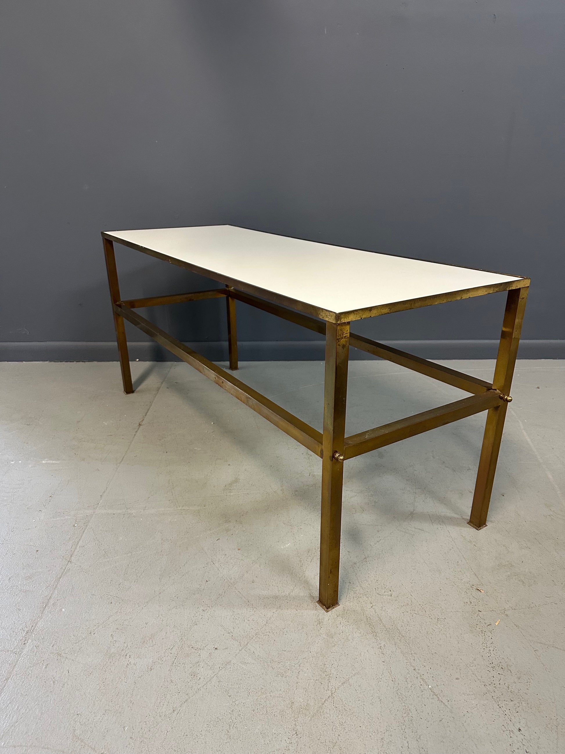 1970s brass console table featuring a sleek white Vitrolite glass top and a minimalist rectangular brass frame with clean lines and mid-century modern influence
