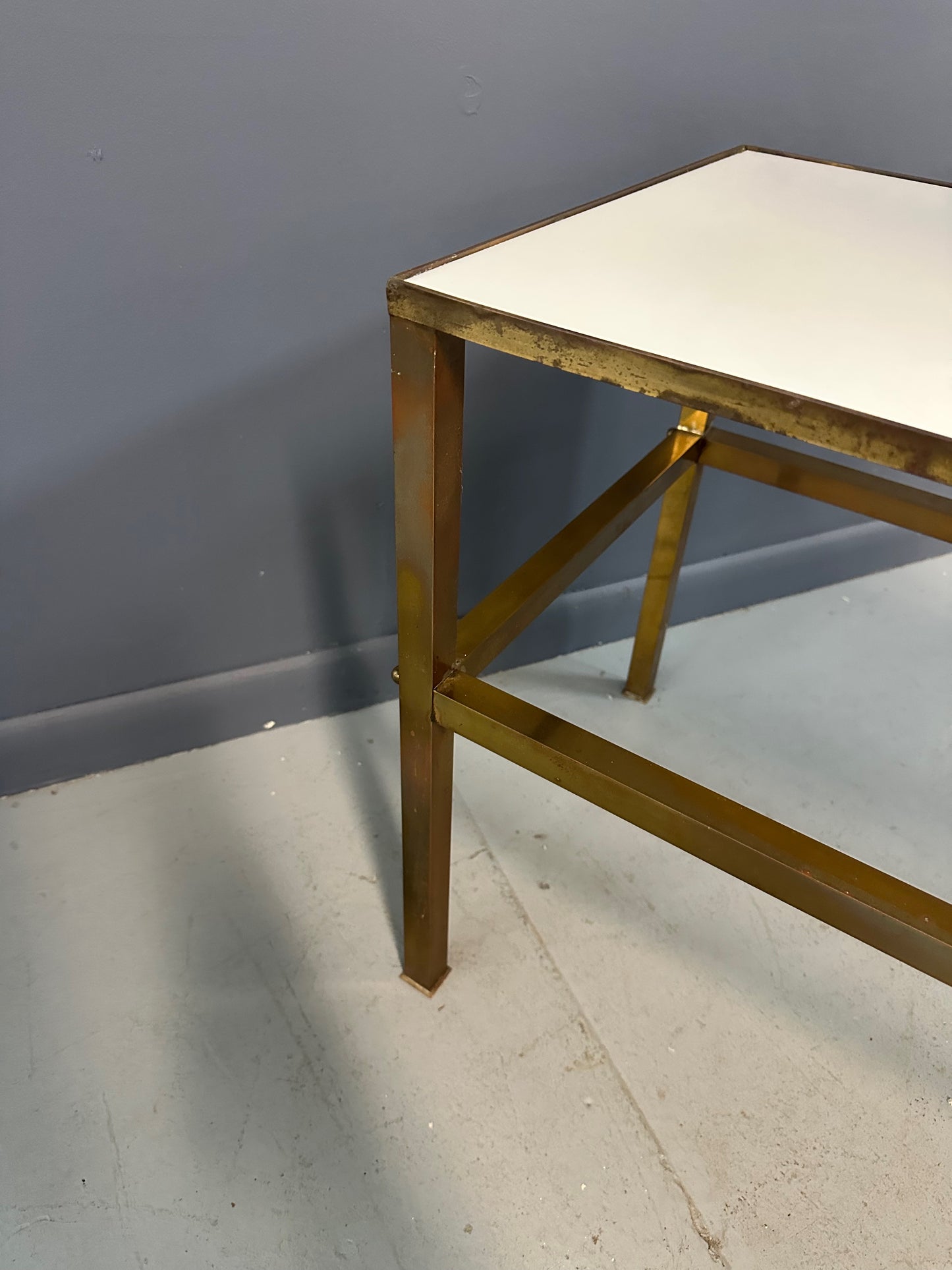 1970s brass console table featuring a sleek white Vitrolite glass top and a minimalist rectangular brass frame with clean lines and mid-century modern influence