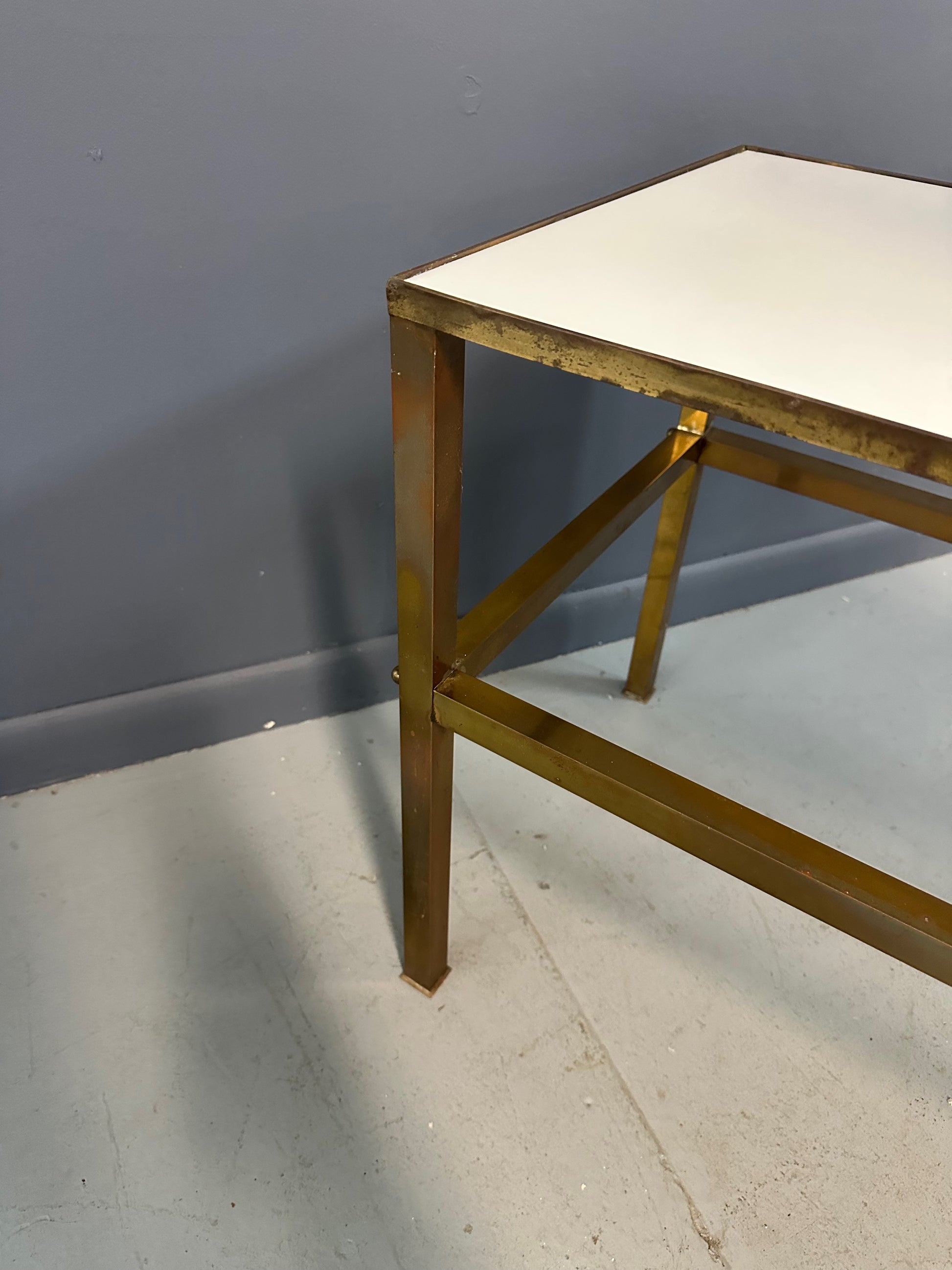 1970s brass console table featuring a sleek white Vitrolite glass top and a minimalist rectangular brass frame with clean lines and mid-century modern influence