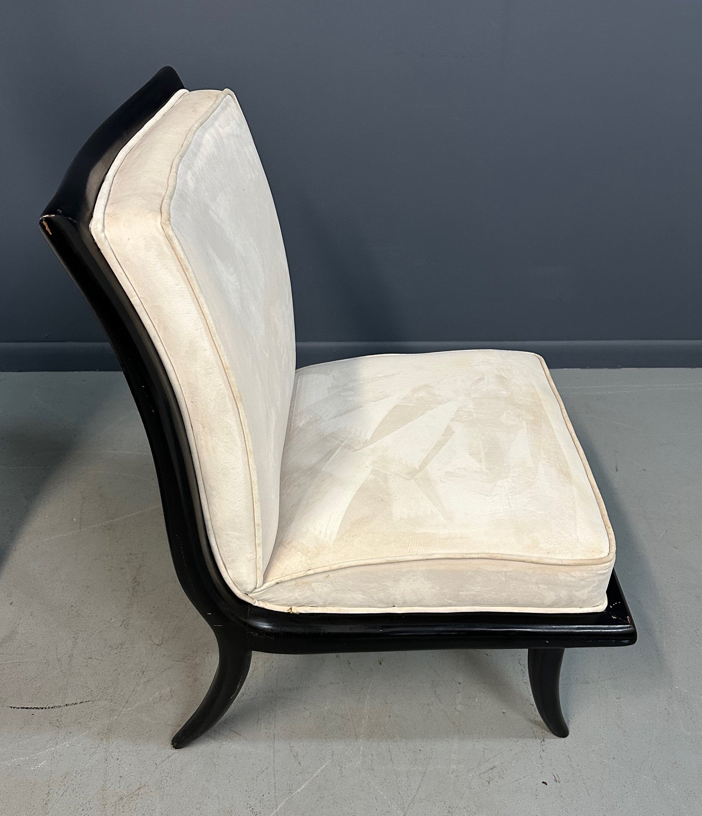 Pair of mid-century modern slipper chairs with ebonized wood frames and cream velvet upholstery, designed in the style of Robsjohn-Gibbings, featuring elegant curves and tapered legs