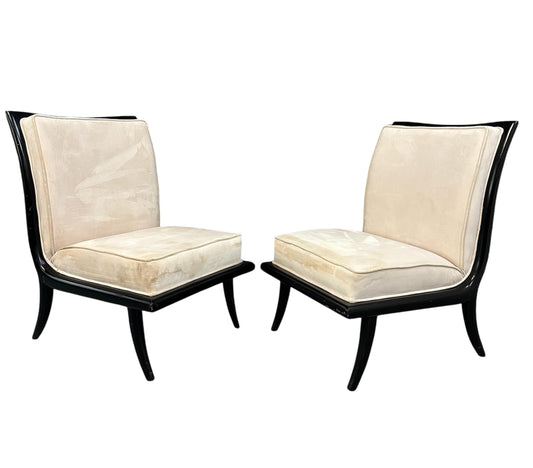 Pair of mid-century modern slipper chairs with ebonized wood frames and cream velvet upholstery, designed in the style of Robsjohn-Gibbings, featuring elegant curves and tapered legs