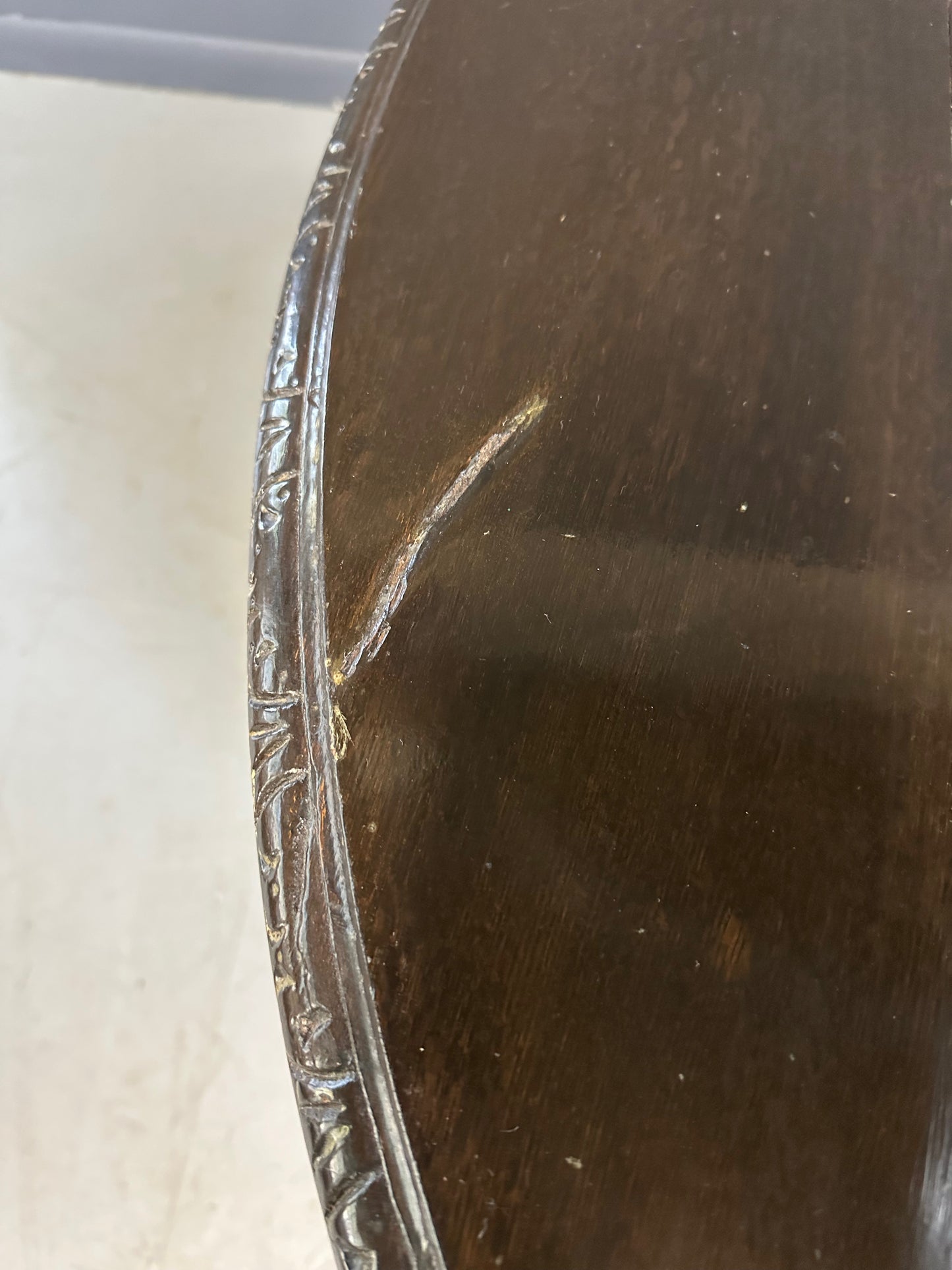 Antique French early 1900s round dining table crafted in rich fruitwood with a carved apron and an intricately detailed pedestal base featuring scrollwork and foliage motifs