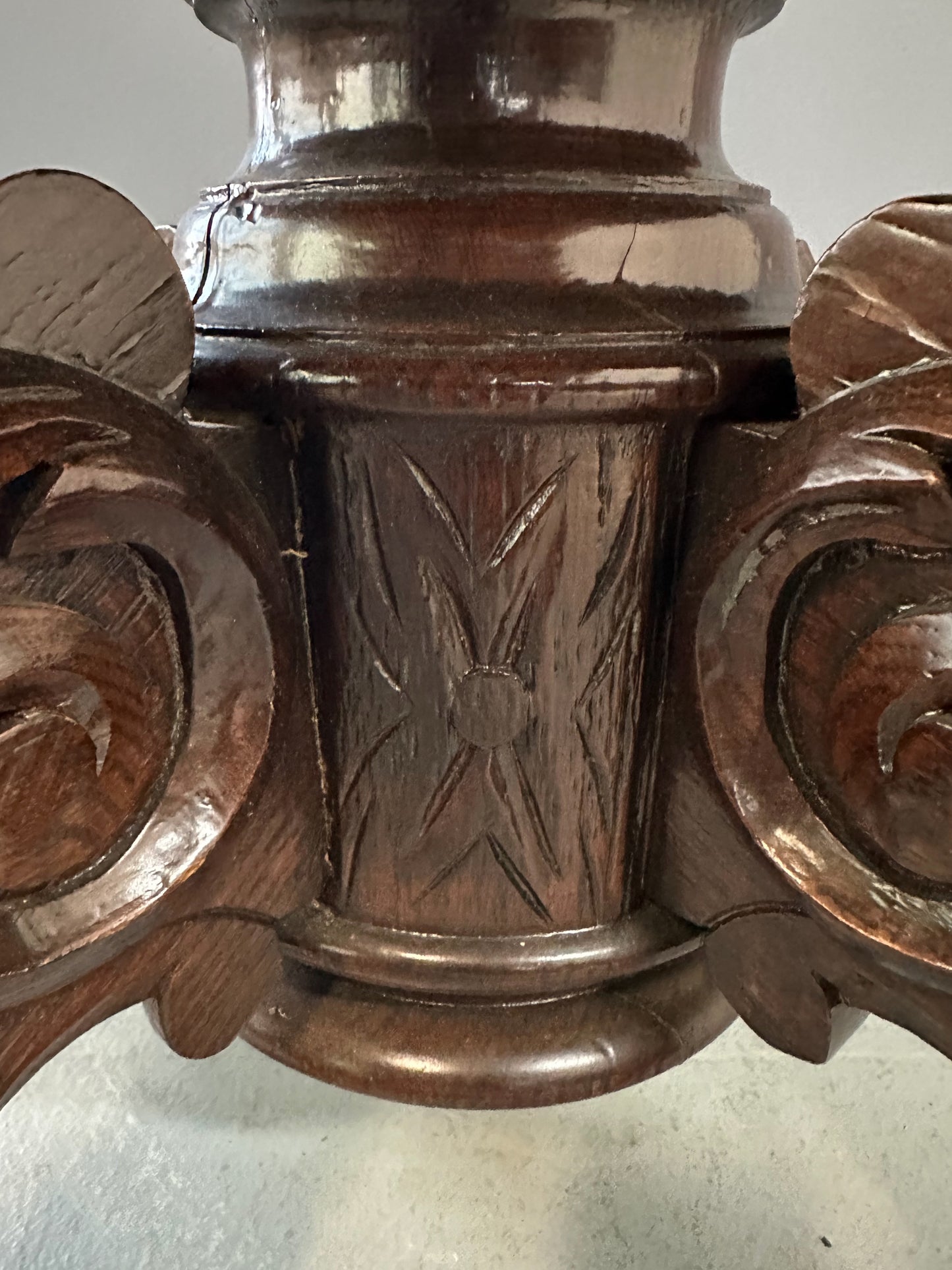 Antique French early 1900s round dining table crafted in rich fruitwood with a carved apron and an intricately detailed pedestal base featuring scrollwork and foliage motifs