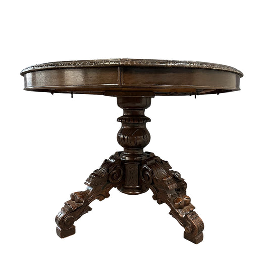 Antique French early 1900s round dining table crafted in rich fruitwood with a carved apron and an intricately detailed pedestal base featuring scrollwork and foliage motifs