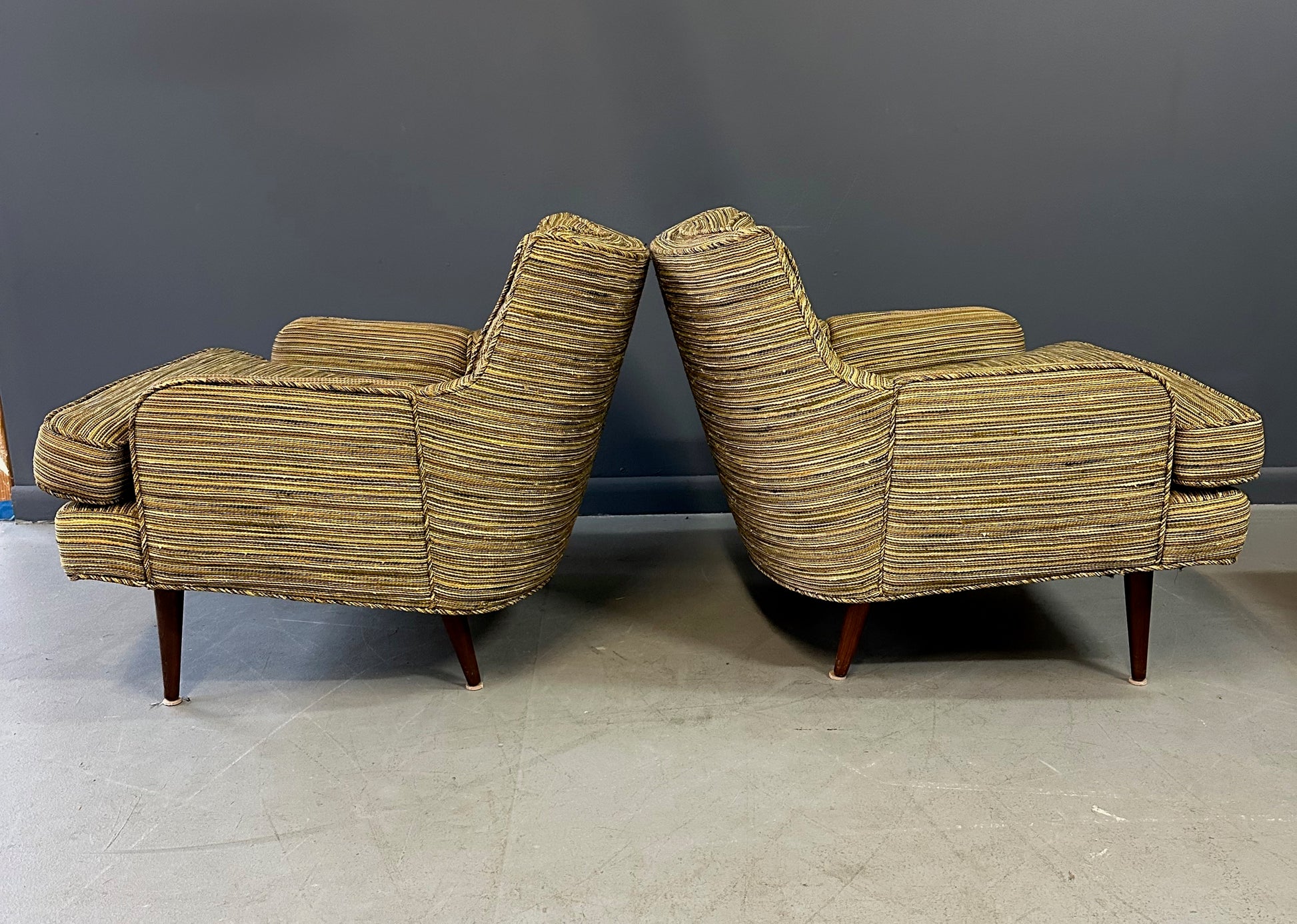 Pair of mid-century lounge chairs with tapered walnut legs, upholstered in original striped multicolor fabric with tufted backs and plush cushions