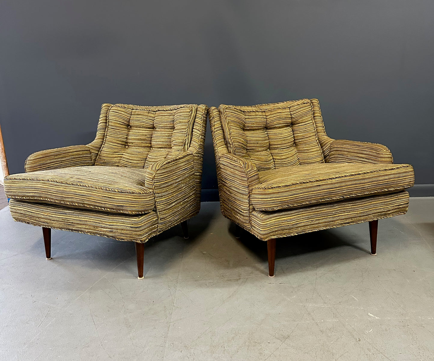 Pair of mid-century lounge chairs with tapered walnut legs, upholstered in original striped multicolor fabric with tufted backs and plush cushions