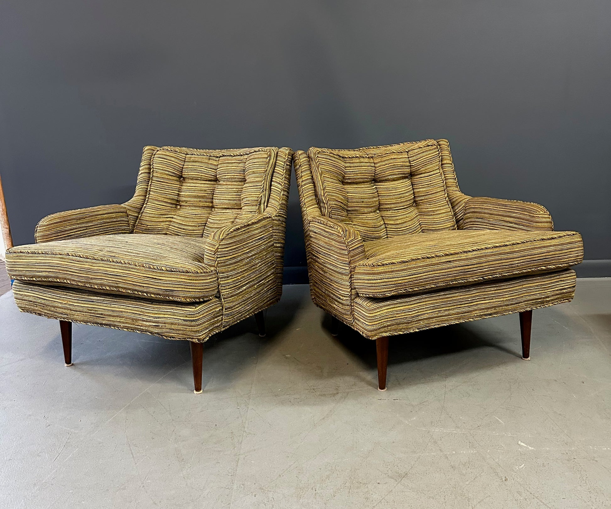 Pair of mid-century lounge chairs with tapered walnut legs, upholstered in original striped multicolor fabric with tufted backs and plush cushions