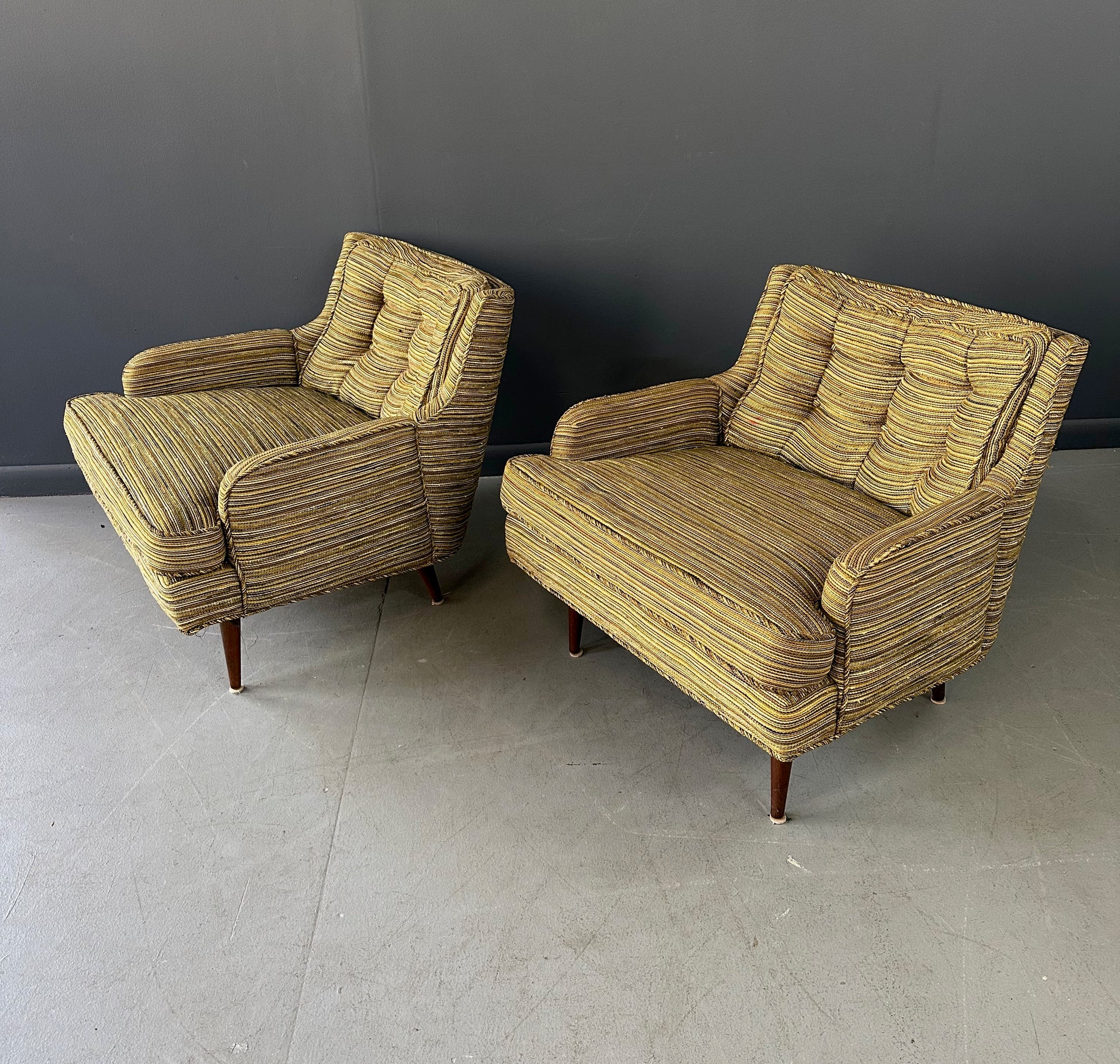 Pair of mid-century lounge chairs with tapered walnut legs, upholstered in original striped multicolor fabric with tufted backs and plush cushions