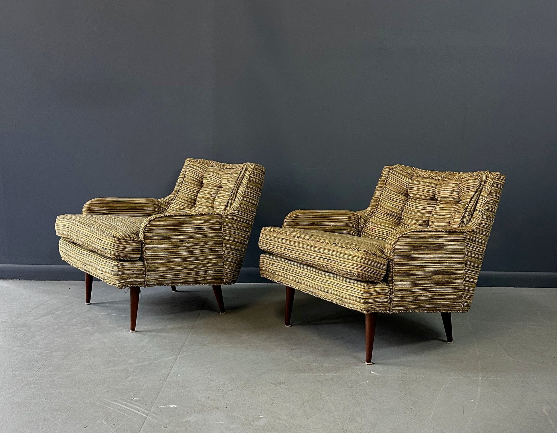 Pair of mid-century lounge chairs with tapered walnut legs, upholstered in original striped multicolor fabric with tufted backs and plush cushions
