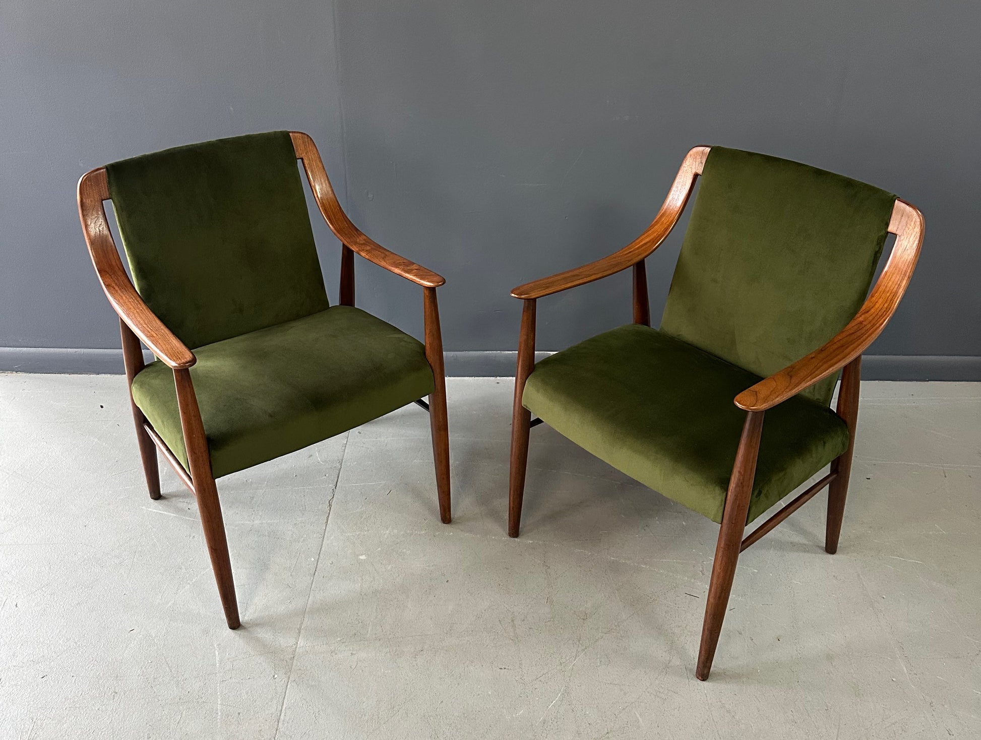 Pair of Danish lounge chairs in the style of Peter Hvidt, featuring sculptural walnut frames and green velvet upholstered seats and backs