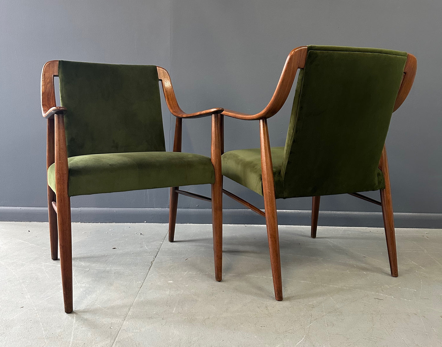 Pair of Danish lounge chairs in the style of Peter Hvidt, featuring sculptural walnut frames and green velvet upholstered seats and backs