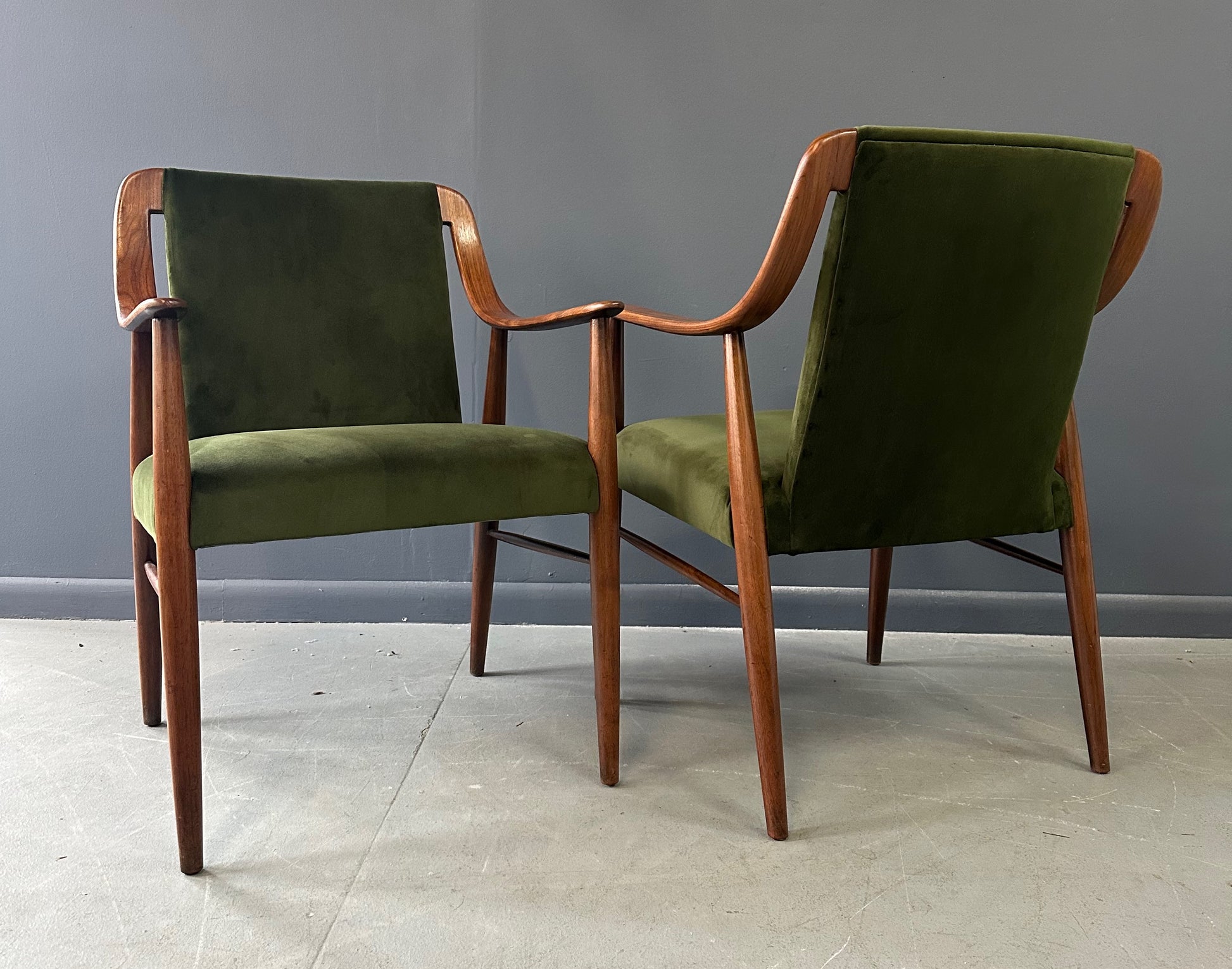 Pair of Danish lounge chairs in the style of Peter Hvidt, featuring sculptural walnut frames and green velvet upholstered seats and backs
