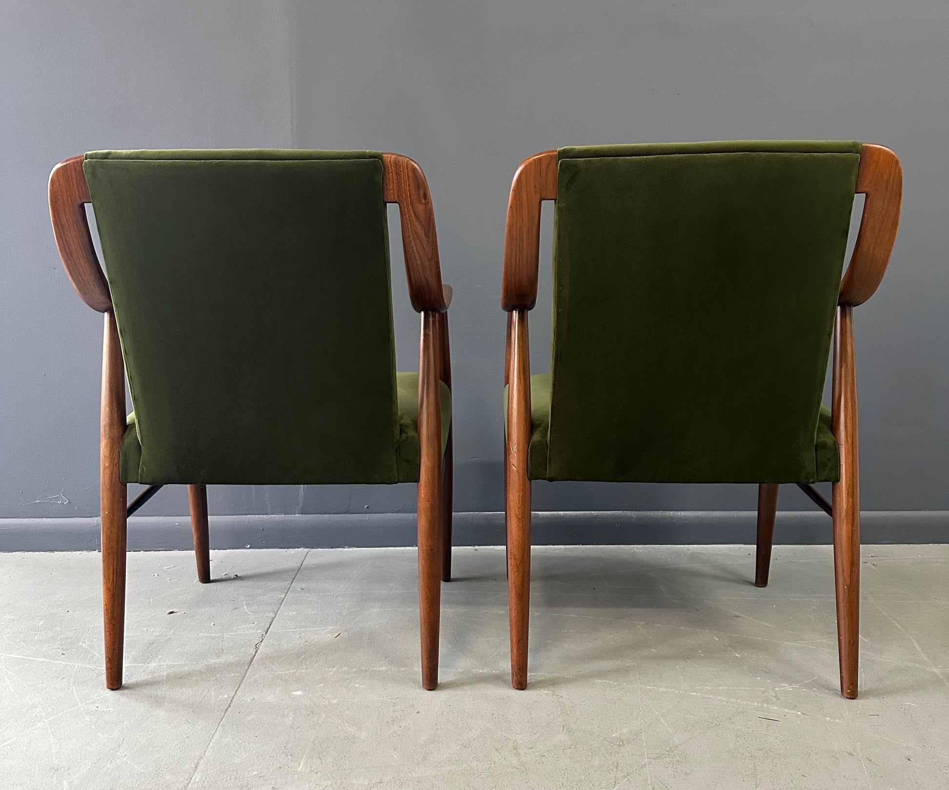 Pair of Danish lounge chairs in the style of Peter Hvidt, featuring sculptural walnut frames and green velvet upholstered seats and backs