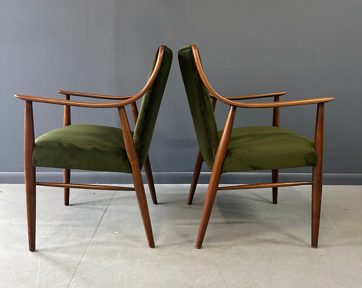 Pair of Danish lounge chairs in the style of Peter Hvidt, featuring sculptural walnut frames and green velvet upholstered seats and backs