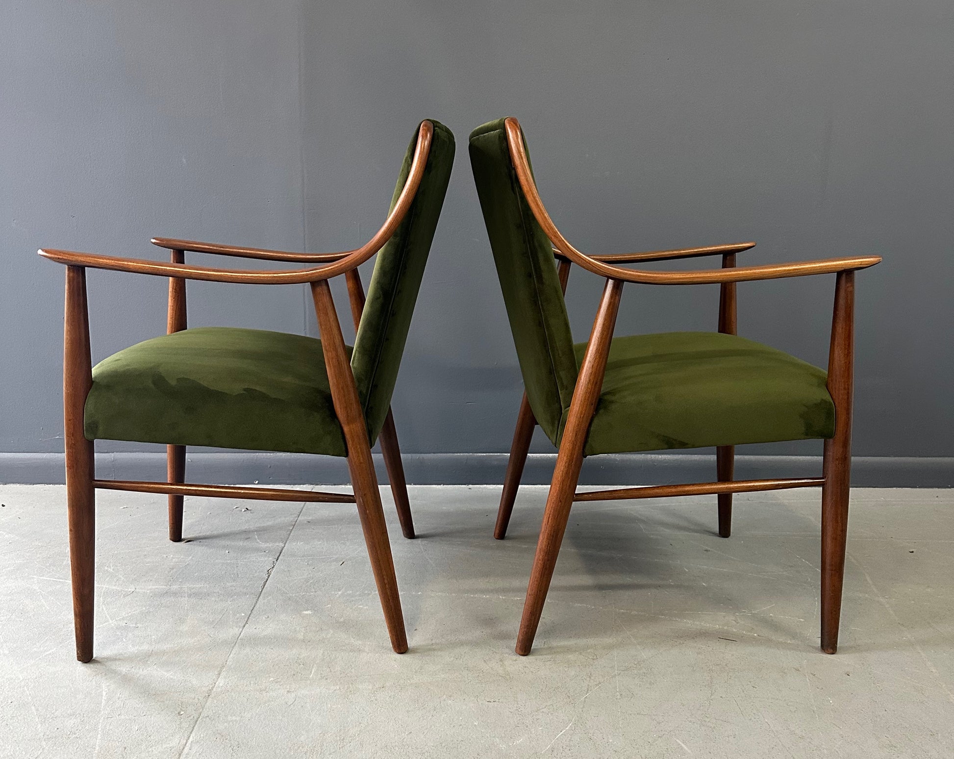 Pair of Danish lounge chairs in the style of Peter Hvidt, featuring sculptural walnut frames and green velvet upholstered seats and backs