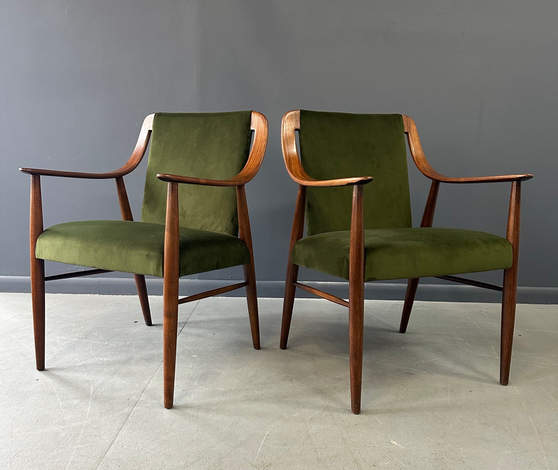 Pair of Danish lounge chairs in the style of Peter Hvidt, featuring sculptural walnut frames and green velvet upholstered seats and backs