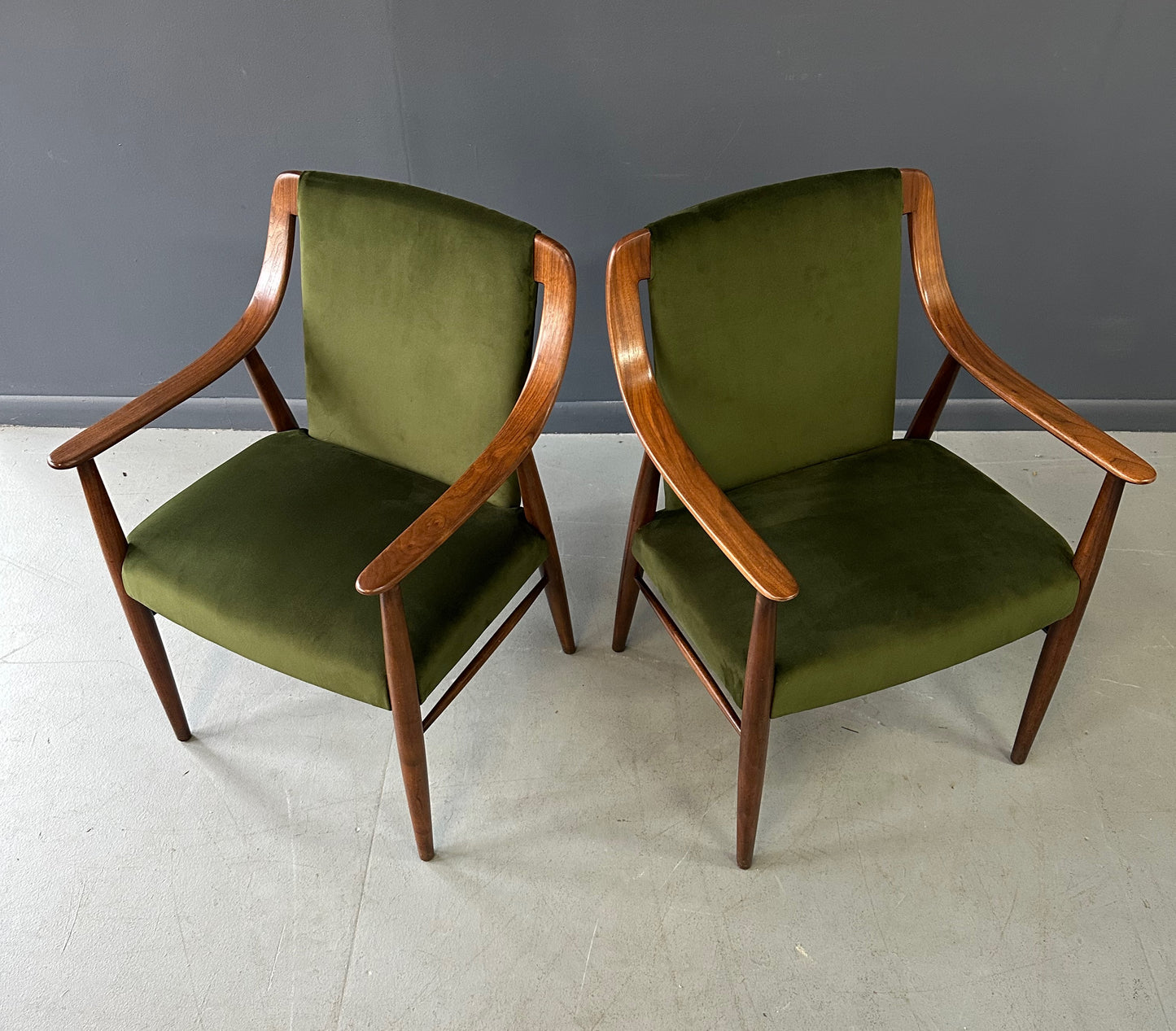 Pair of Danish lounge chairs in the style of Peter Hvidt, featuring sculptural walnut frames and green velvet upholstered seats and backs