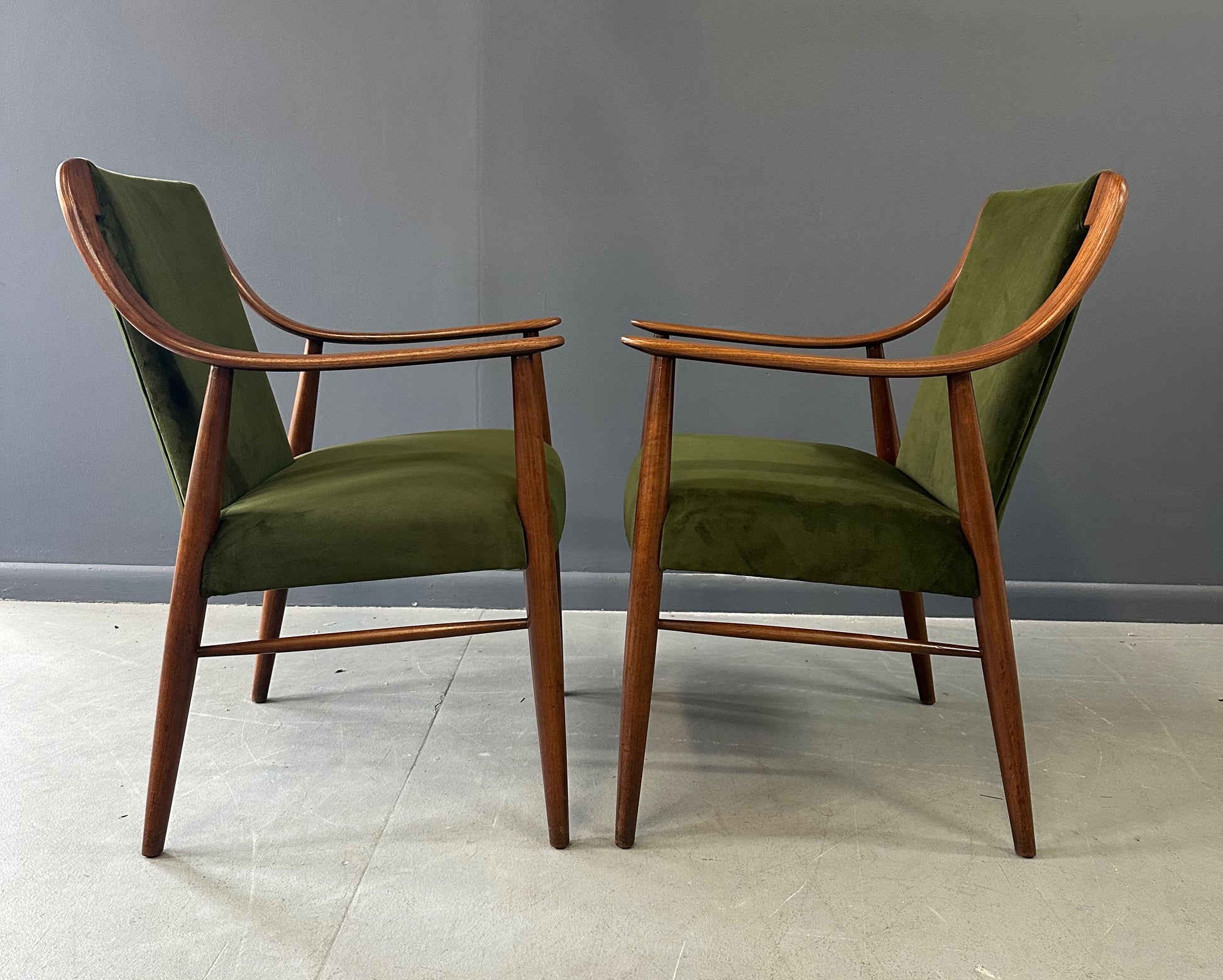 Pair of Danish lounge chairs in the style of Peter Hvidt, featuring sculptural walnut frames and green velvet upholstered seats and backs