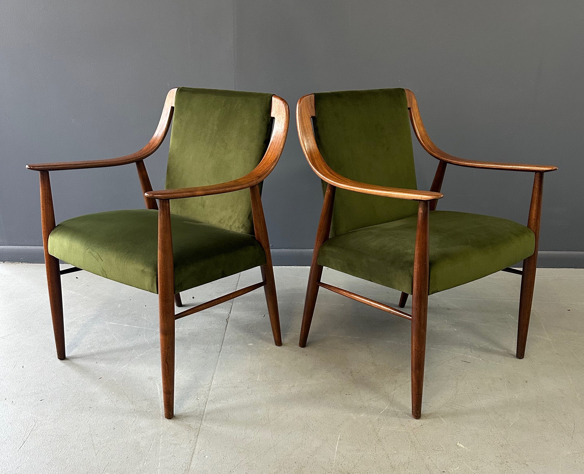 Pair of Danish lounge chairs in the style of Peter Hvidt, featuring sculptural walnut frames and green velvet upholstered seats and backs