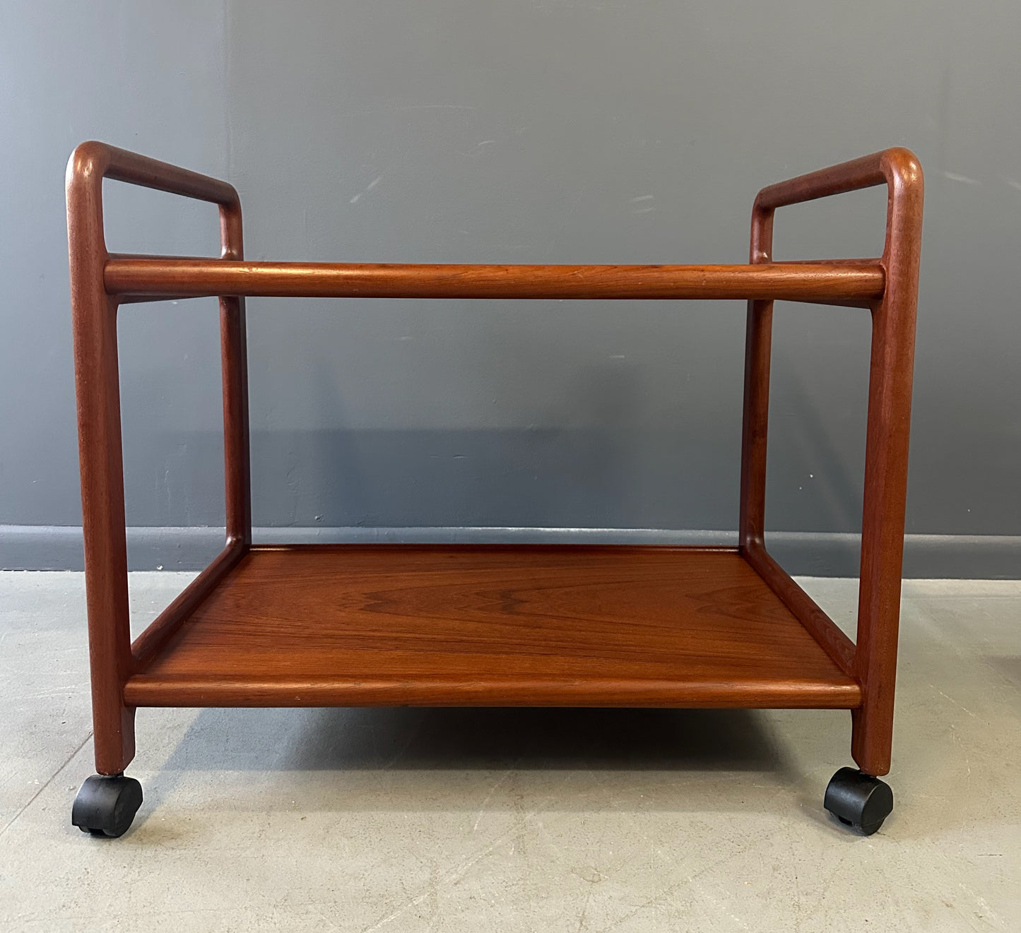 Vintage Danish teak mid-century modern bar cart or drinks trolley with two-tier design, rolling wheels, and minimalist Scandinavian style
