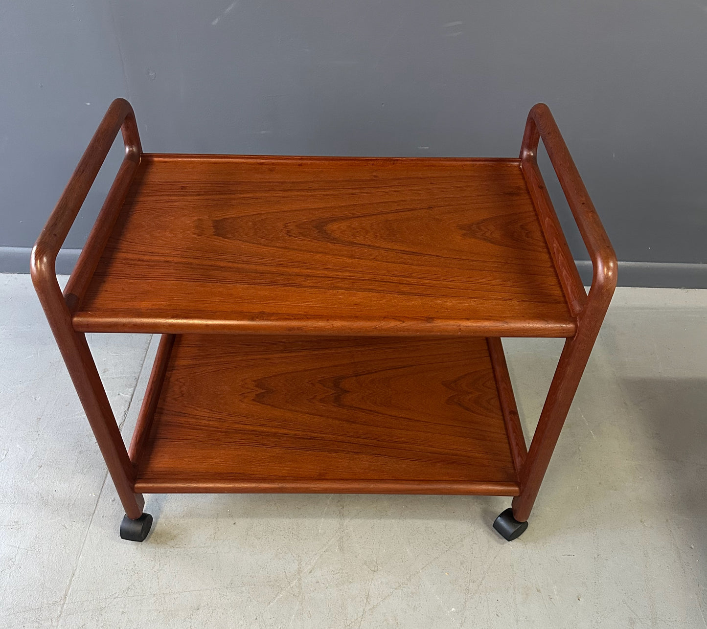Vintage Danish teak mid-century modern bar cart or drinks trolley with two-tier design, rolling wheels, and minimalist Scandinavian style
