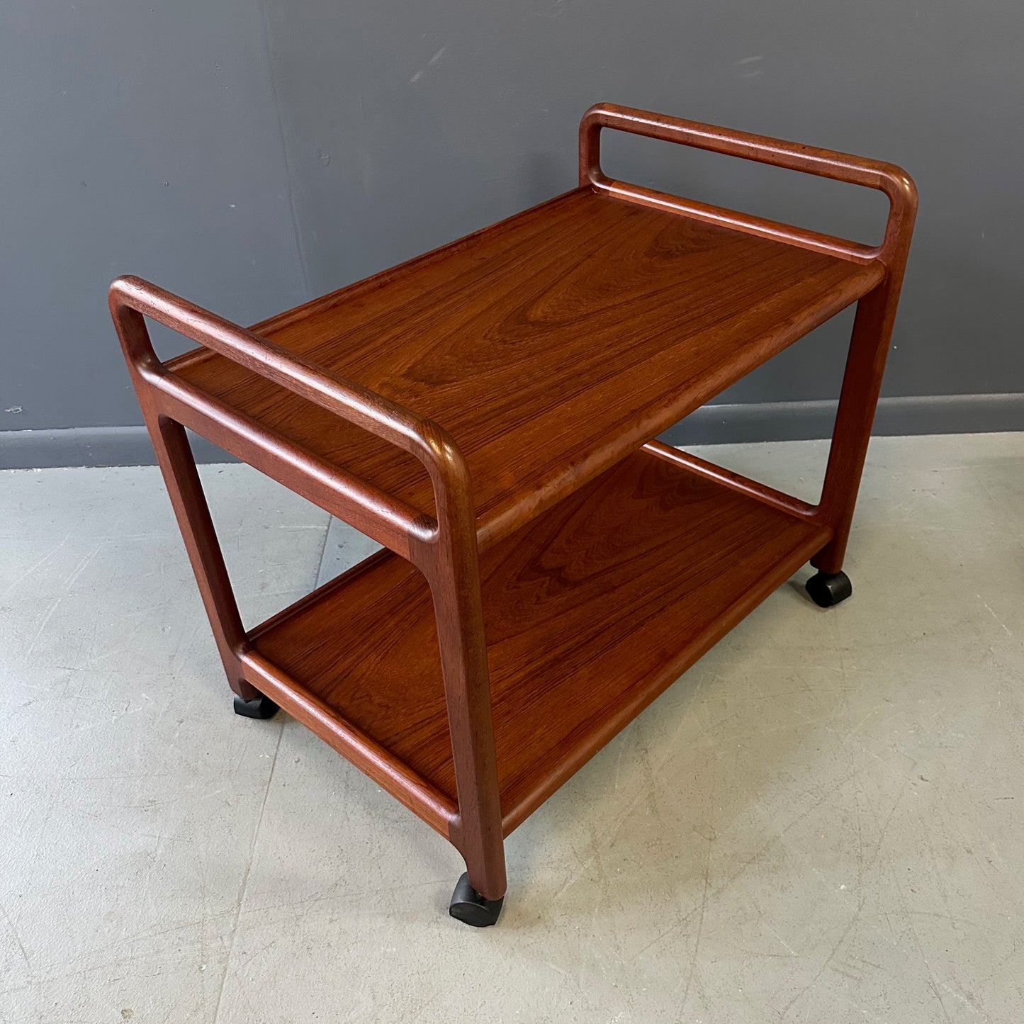 Vintage Danish teak mid-century modern bar cart or drinks trolley with two-tier design, rolling wheels, and minimalist Scandinavian style