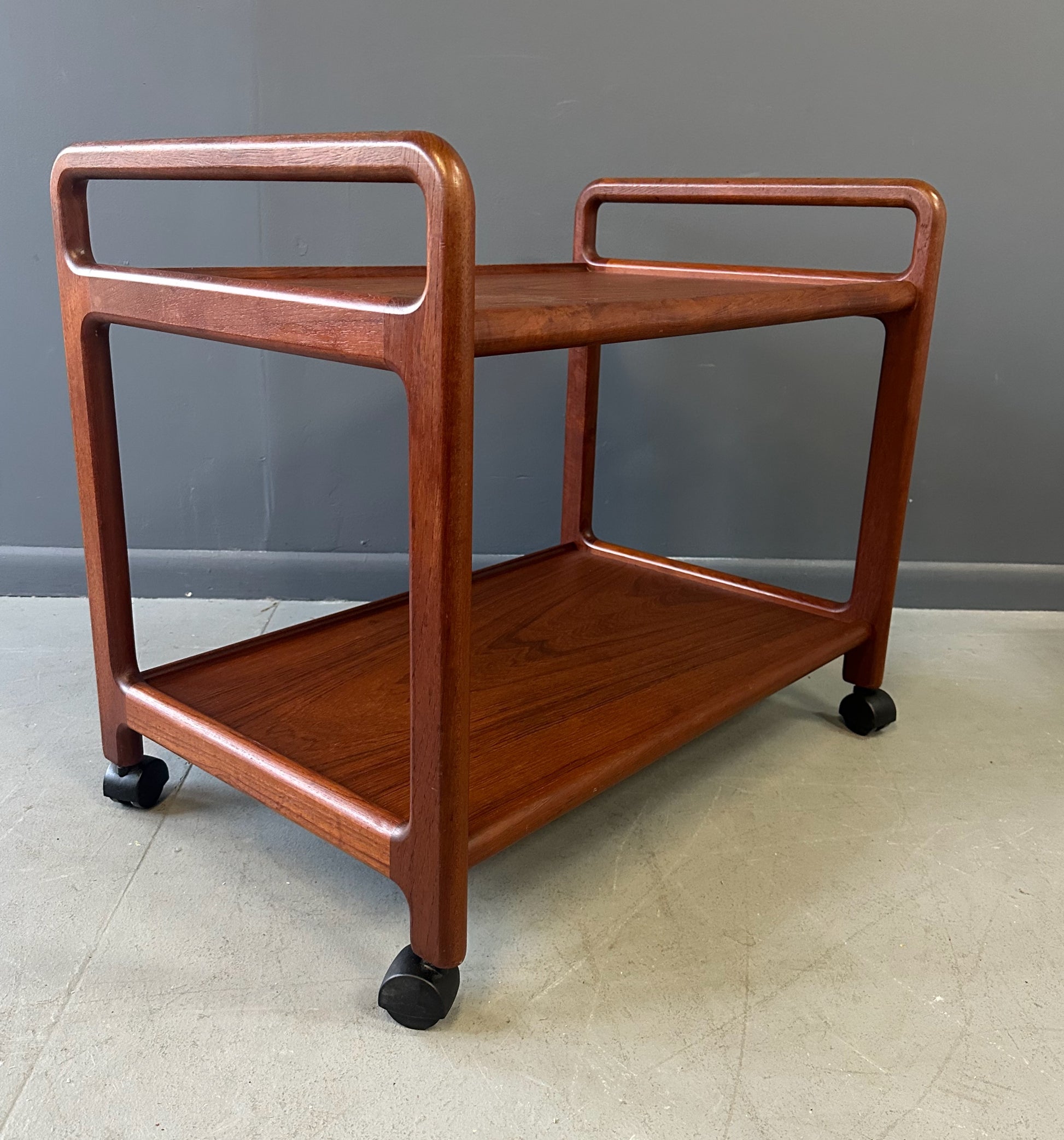 Vintage Danish teak mid-century modern bar cart or drinks trolley with two-tier design, rolling wheels, and minimalist Scandinavian style