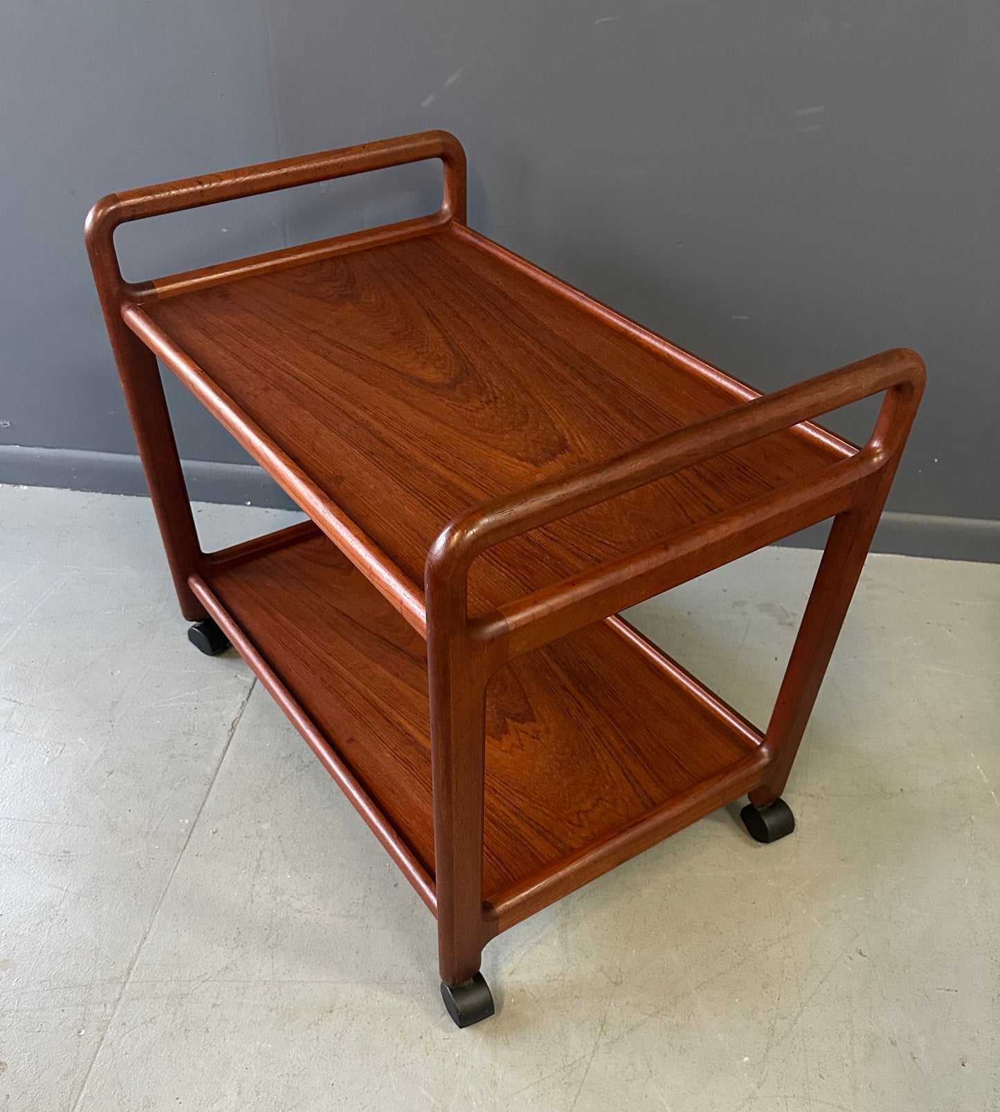 Vintage Danish teak mid-century modern bar cart or drinks trolley with two-tier design, rolling wheels, and minimalist Scandinavian style