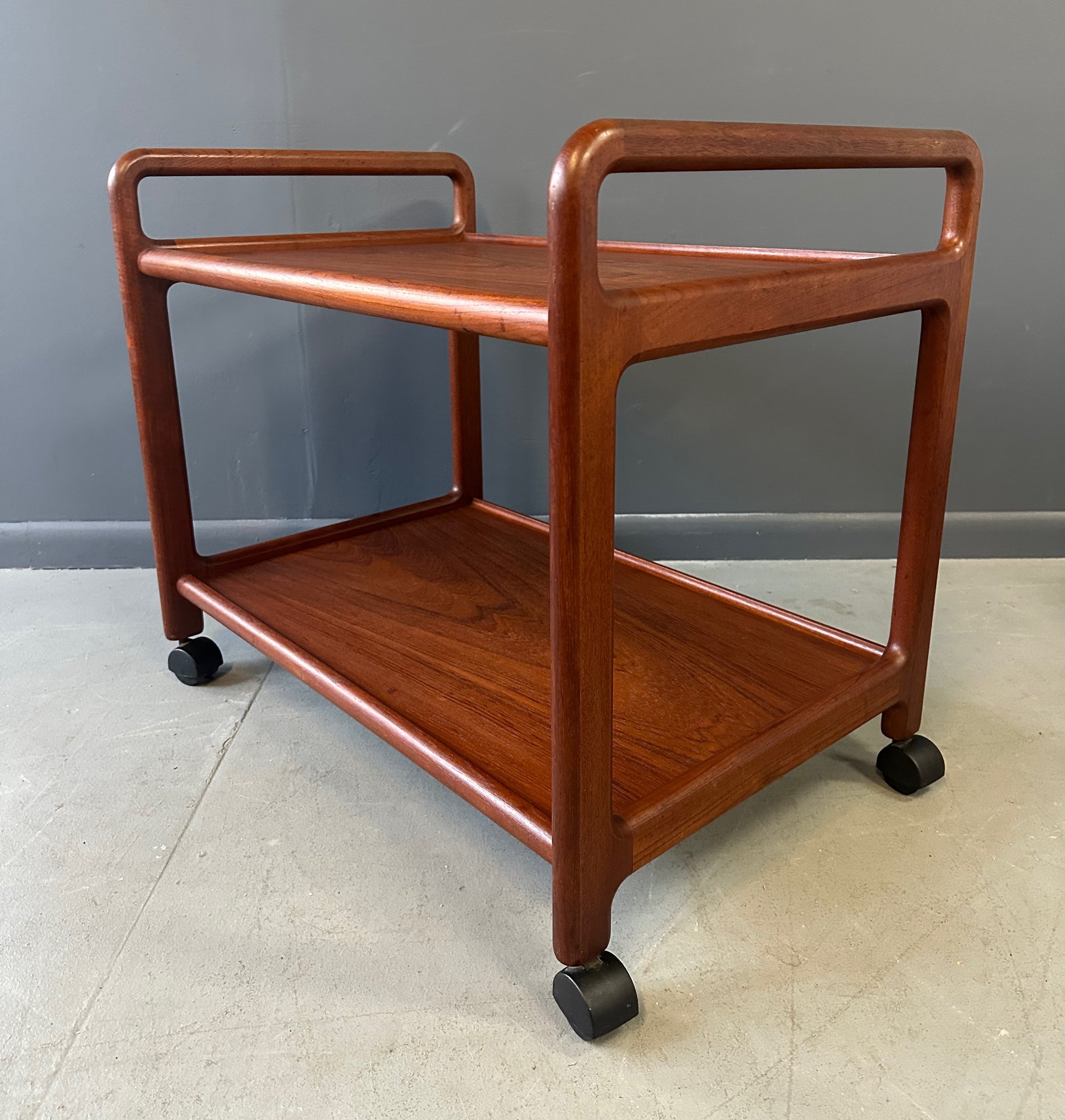Vintage Danish teak mid-century modern bar cart or drinks trolley with two-tier design, rolling wheels, and minimalist Scandinavian style