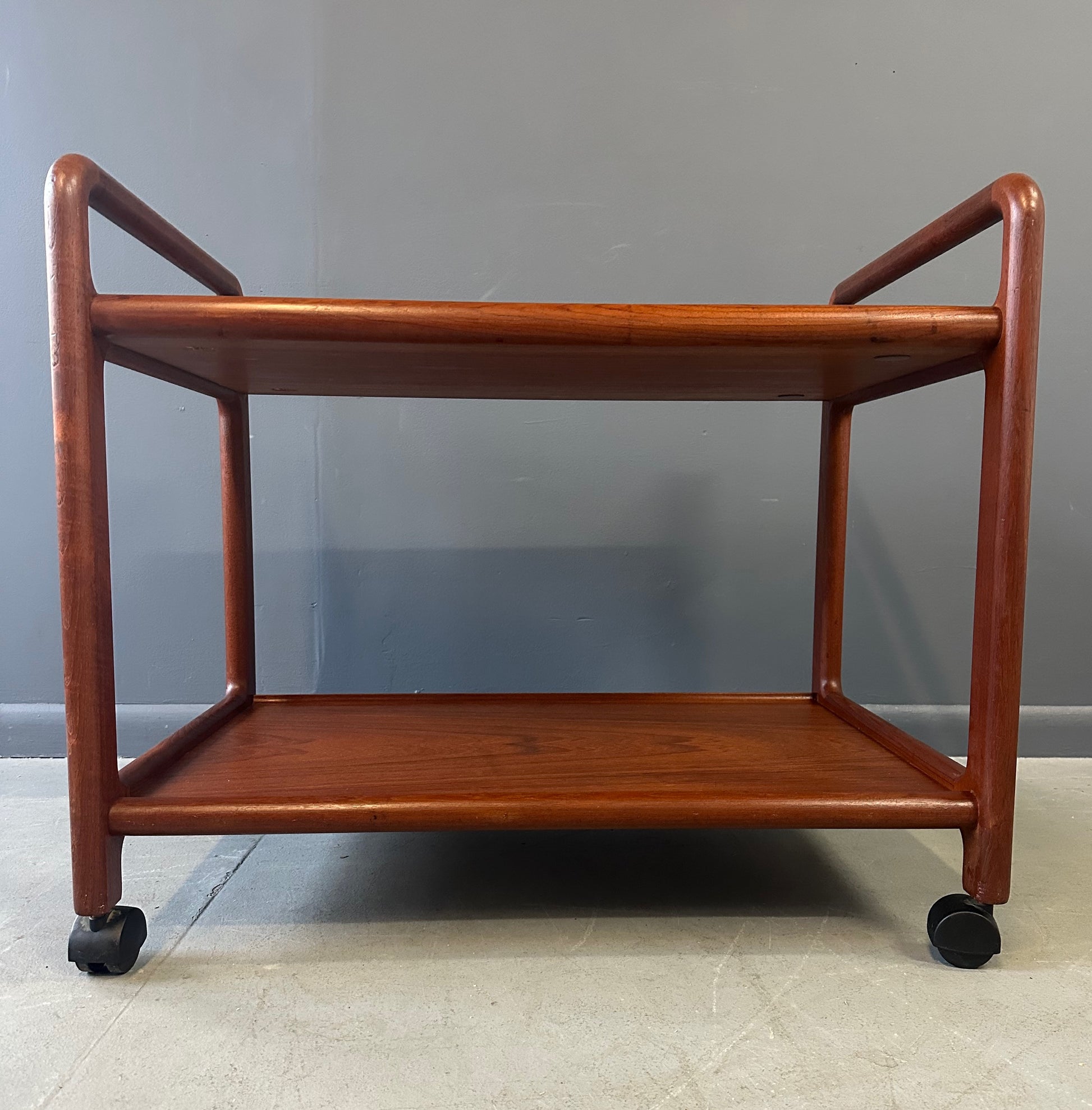 Vintage Danish teak mid-century modern bar cart or drinks trolley with two-tier design, rolling wheels, and minimalist Scandinavian style