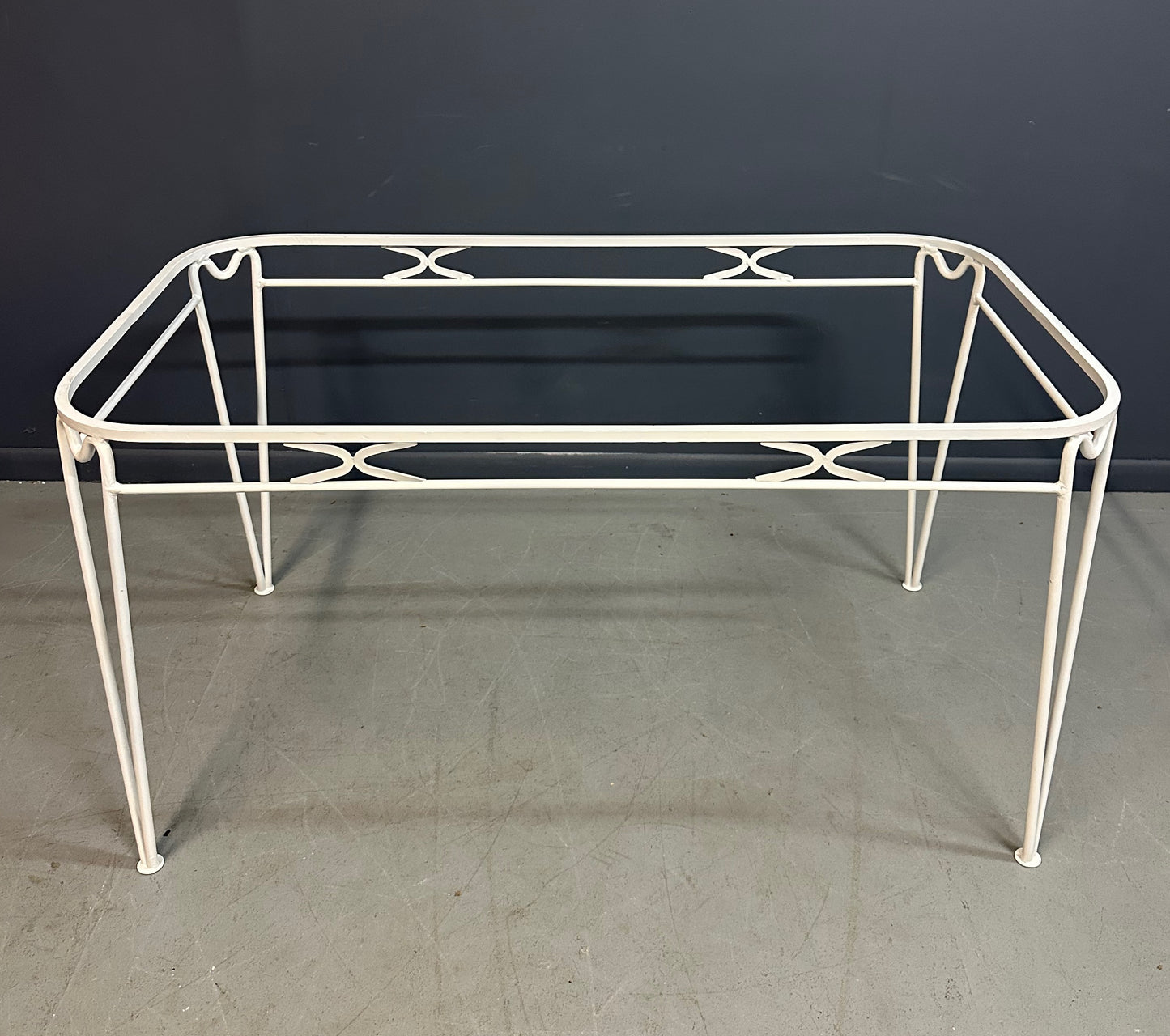 1940s French mid-century modern outdoor dining set featuring six white wrought iron chairs with orange diamond-patterned cushions and a matching table with decorative curved frames