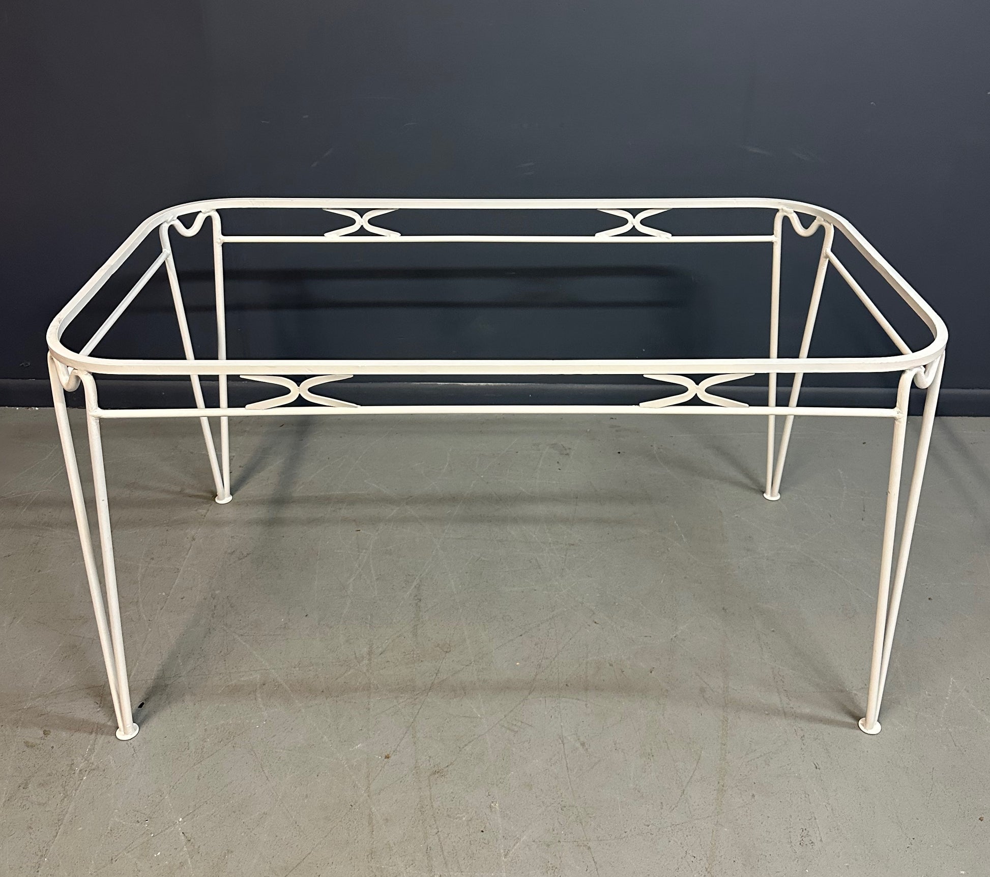 1940s French mid-century modern outdoor dining set featuring six white wrought iron chairs with orange diamond-patterned cushions and a matching table with decorative curved frames