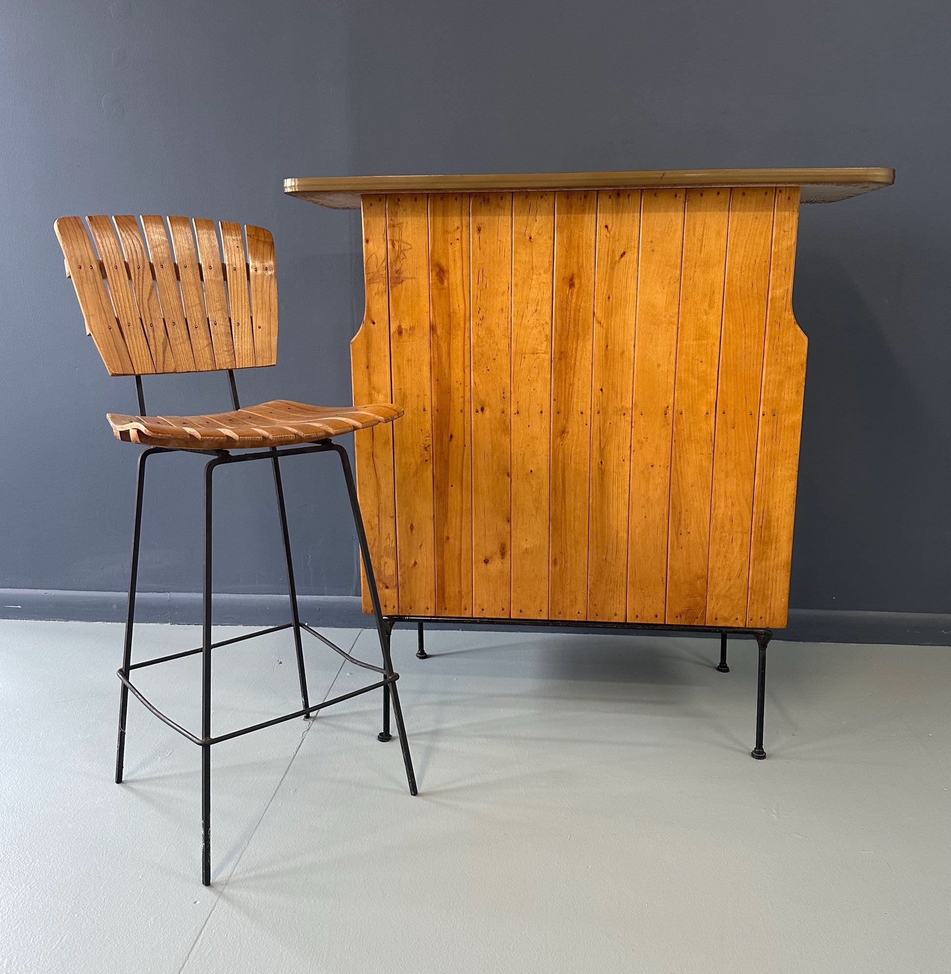Mid-Century Modern dry bar console with matching stool by Arthur Umanoff, 1950s, featuring slatted wood panels, iron legs, and a curved wooden seat and backrest with minimalist black metal framing