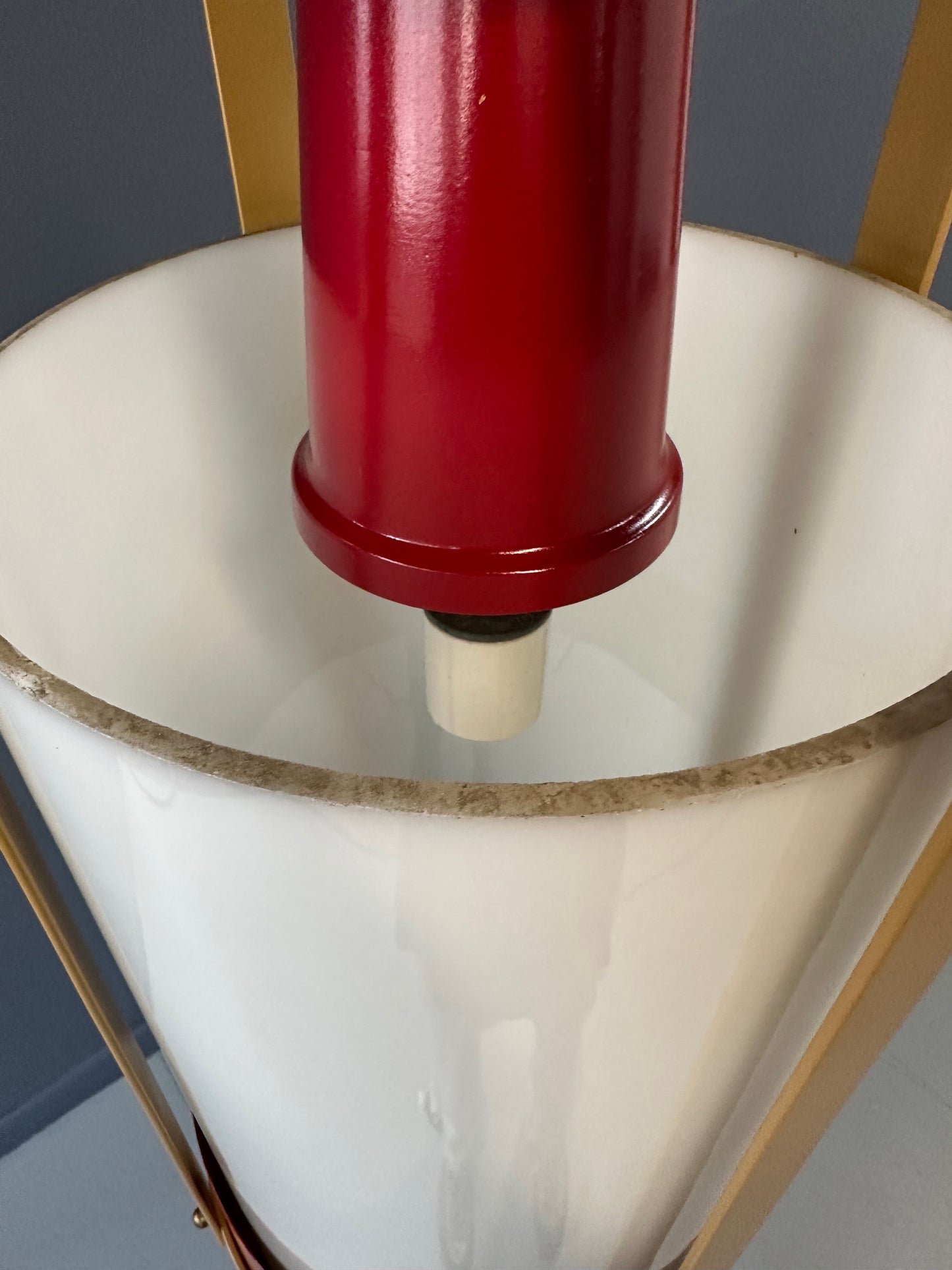 Pair of large pendant lights featuring cylindrical white glass shades encased in red and brass-colored metal frames, suspended by chains for ceiling mounting
