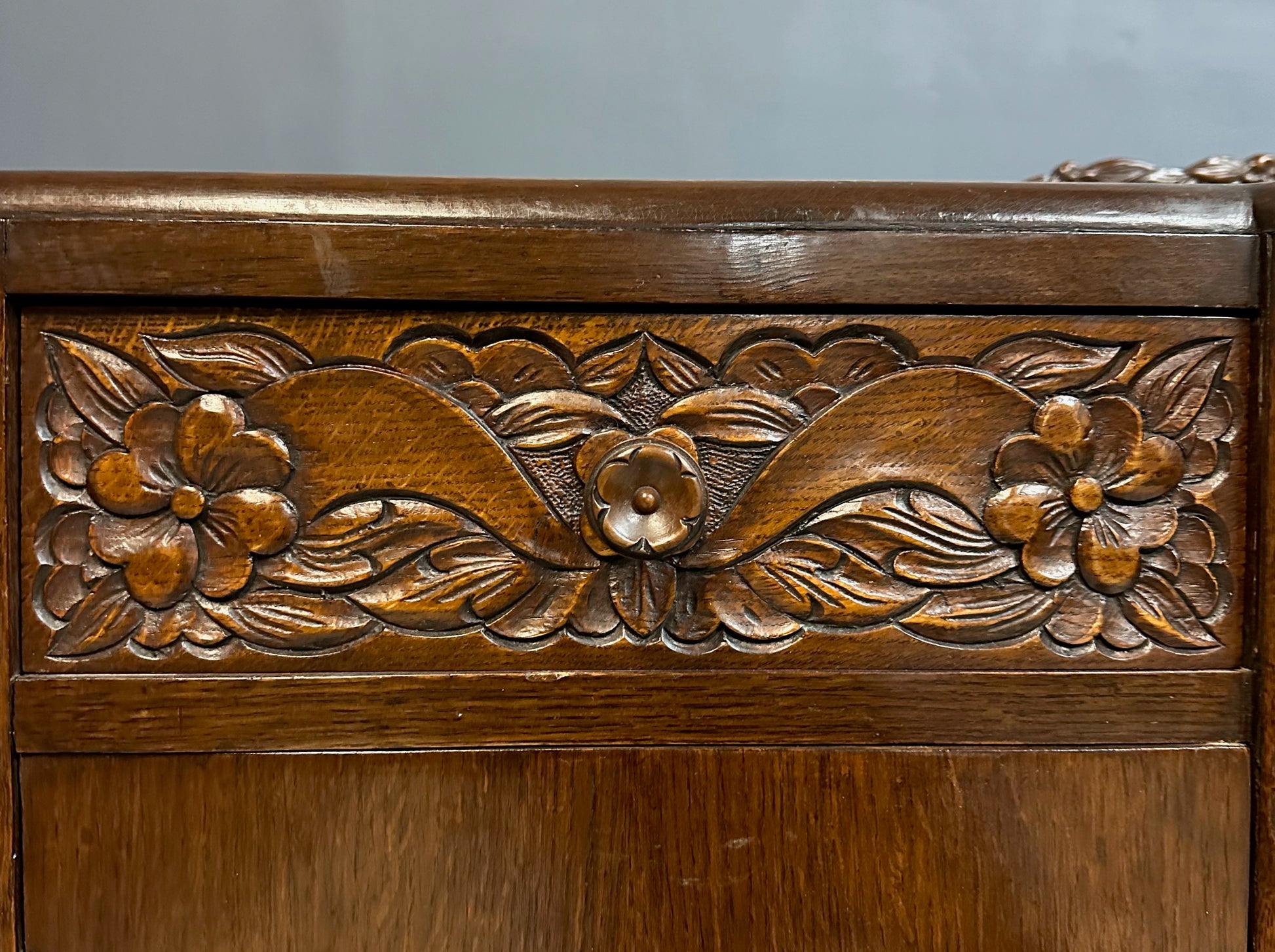 1920s English Art Nouveau sideboard in oak with ornate floral and vine hand-carving, three-door storage, and bun feet