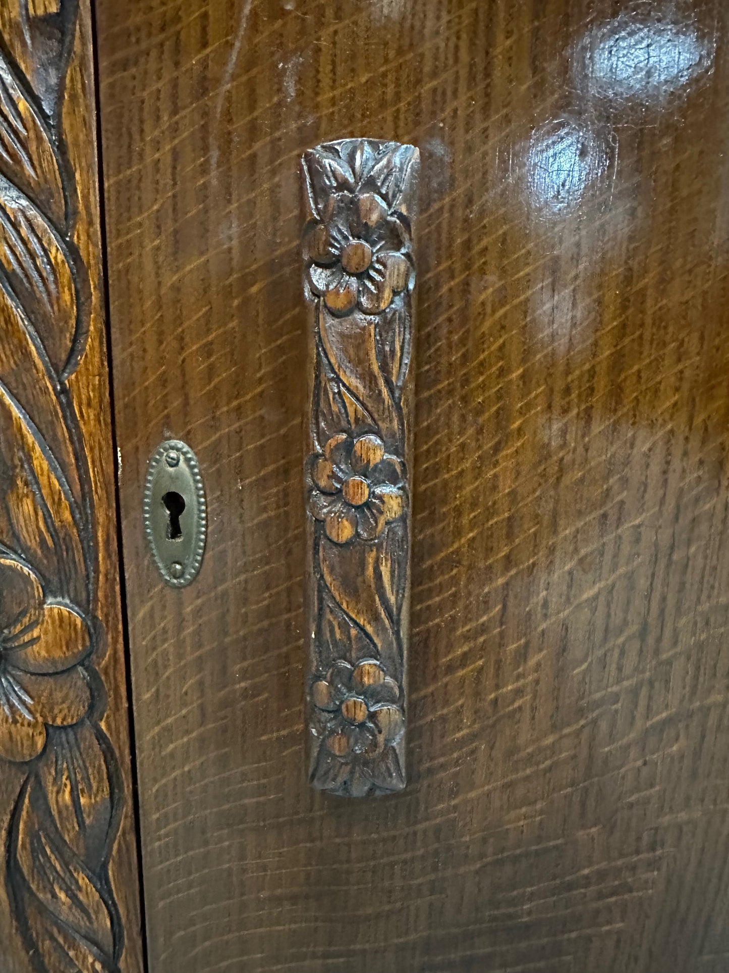 1920s English Art Nouveau sideboard in oak with ornate floral and vine hand-carving, three-door storage, and bun feet