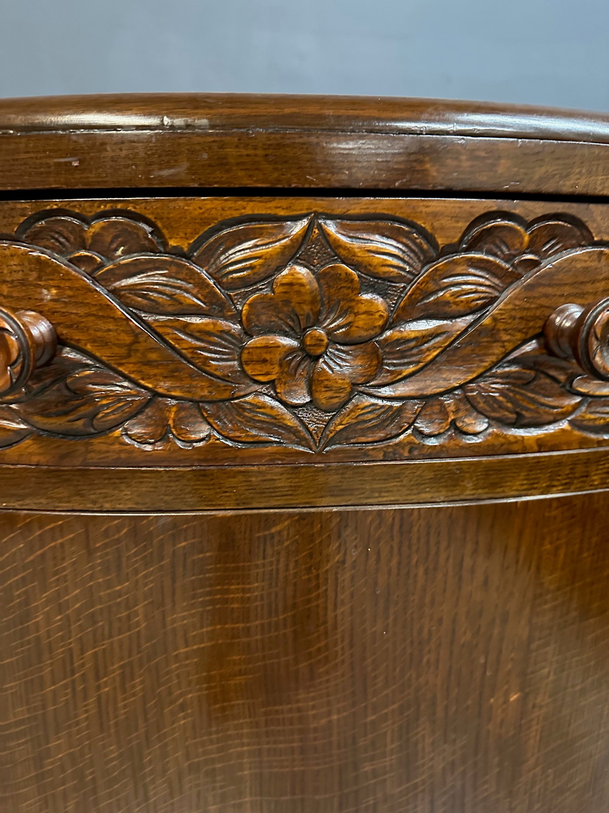 1920s English Art Nouveau sideboard in oak with ornate floral and vine hand-carving, three-door storage, and bun feet