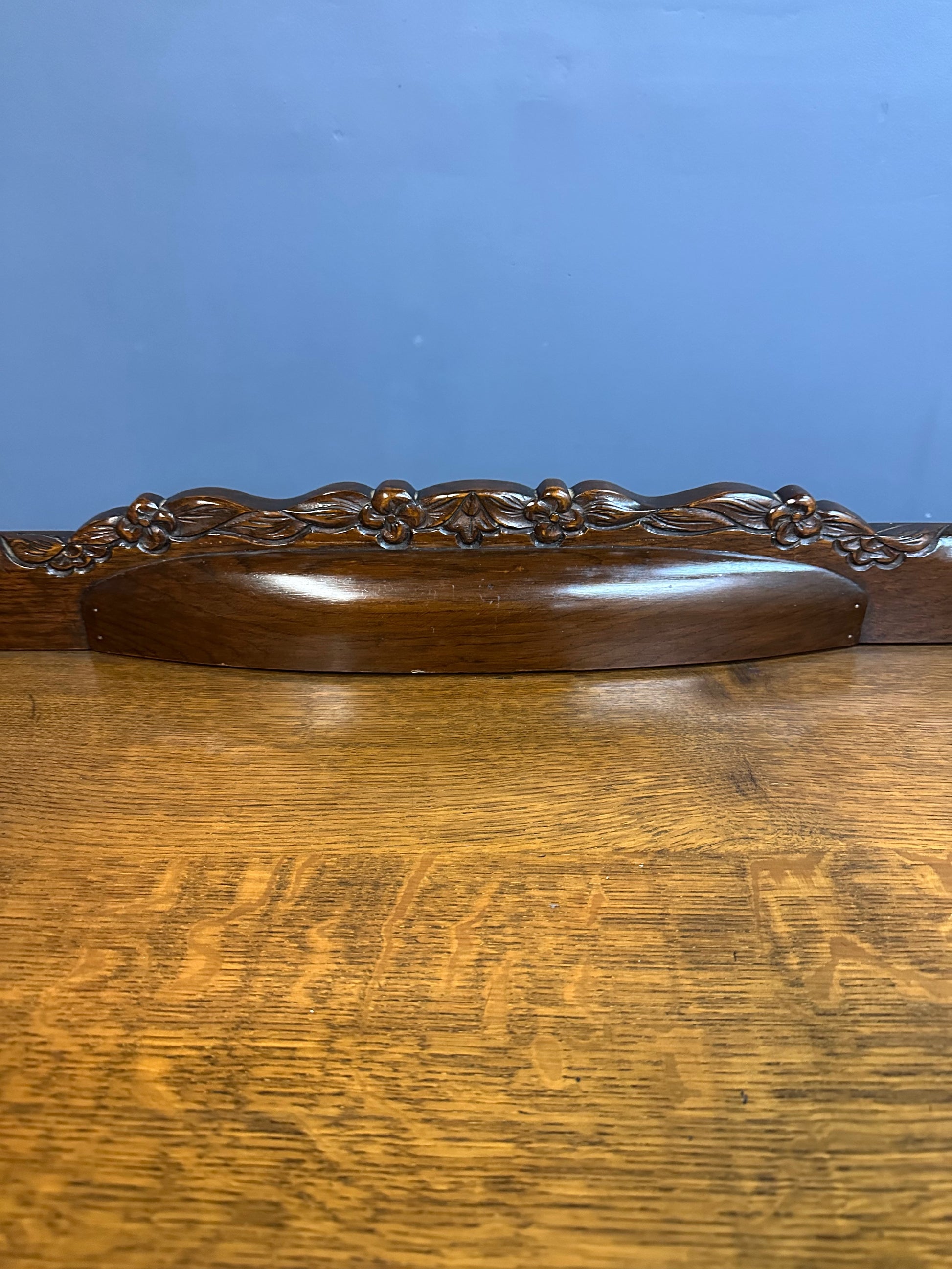 1920s English Art Nouveau sideboard in oak with ornate floral and vine hand-carving, three-door storage, and bun feet
