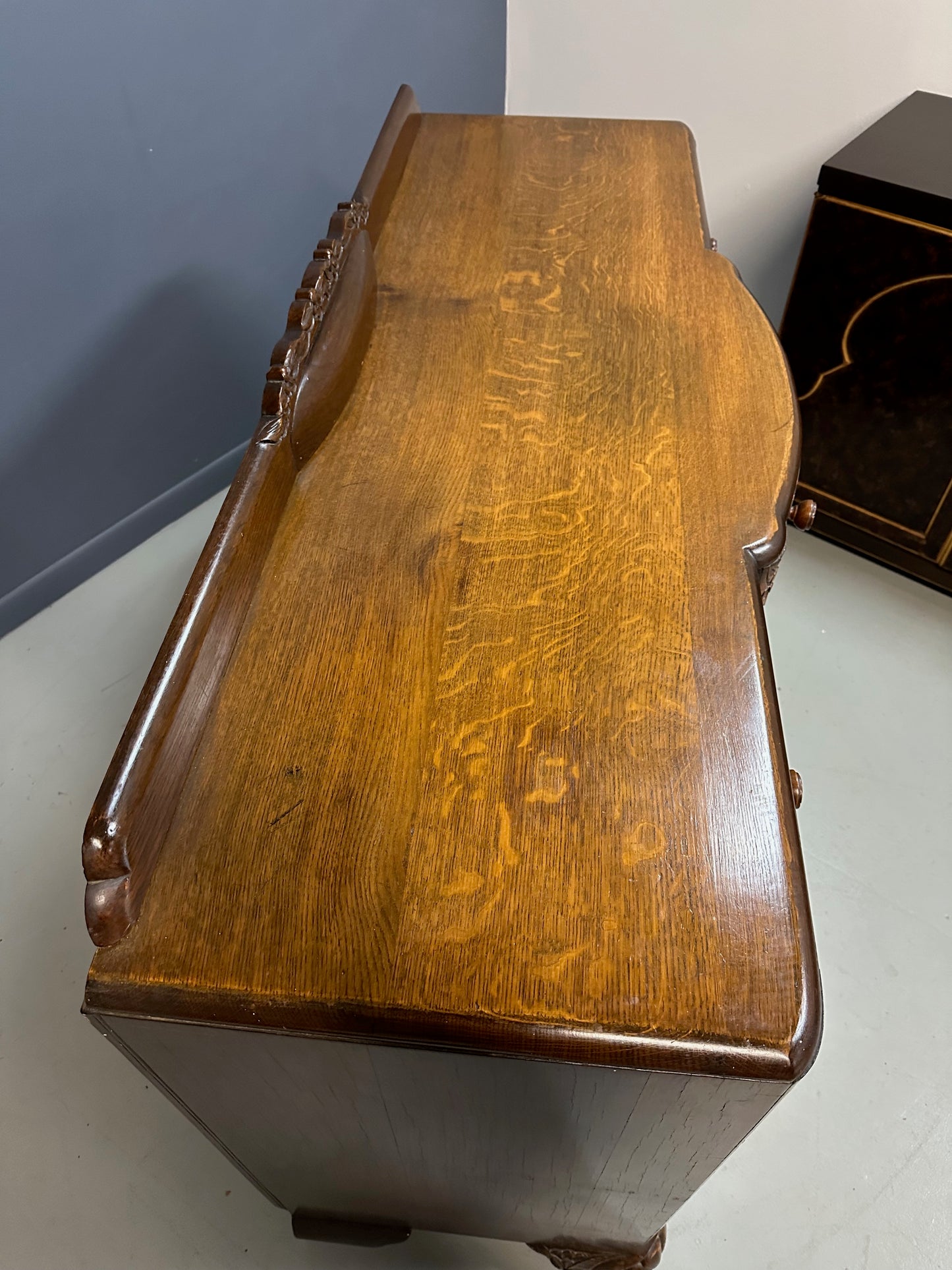 1920s English Art Nouveau sideboard in oak with ornate floral and vine hand-carving, three-door storage, and bun feet