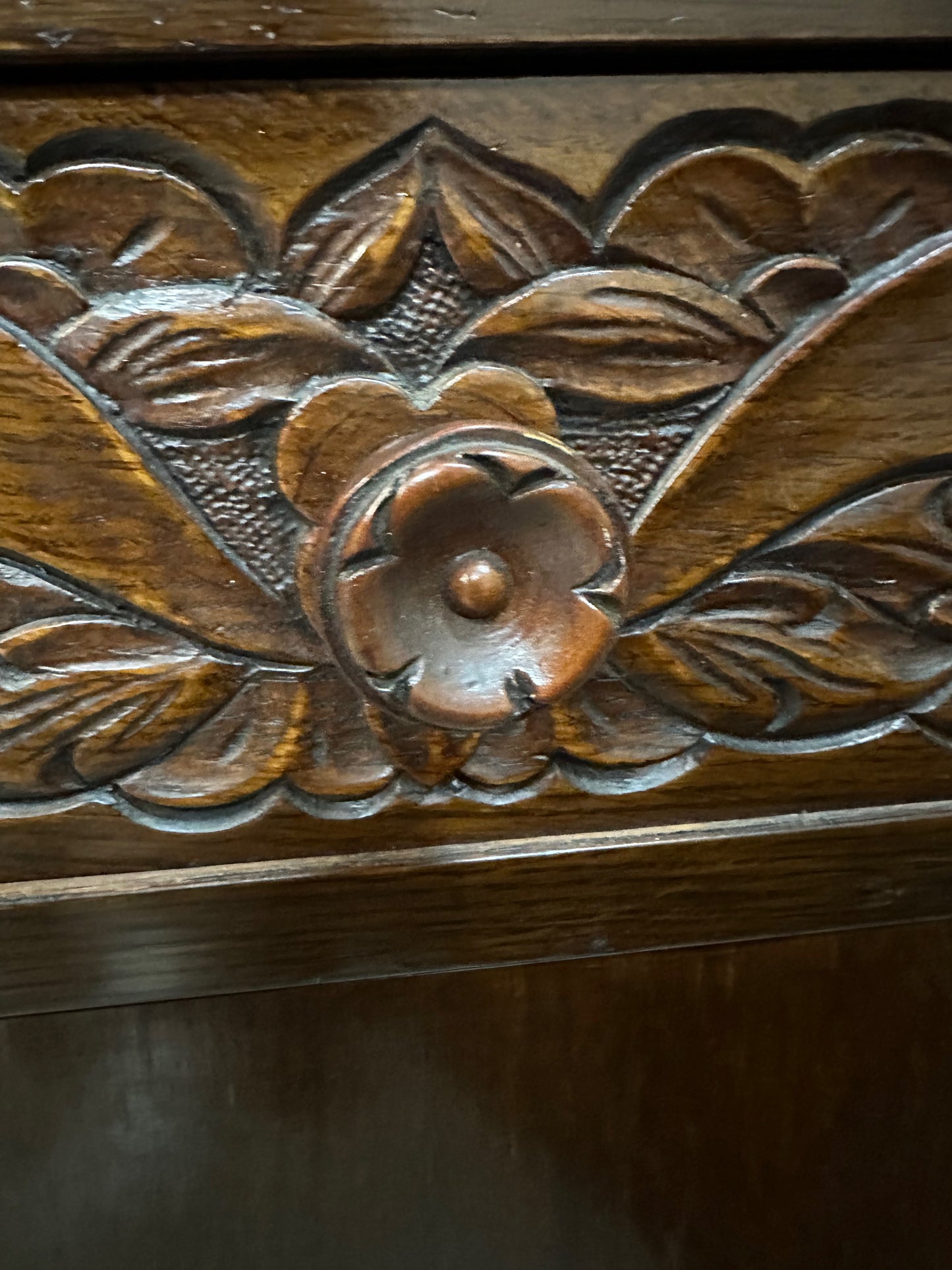 1920s English Art Nouveau sideboard in oak with ornate floral and vine hand-carving, three-door storage, and bun feet